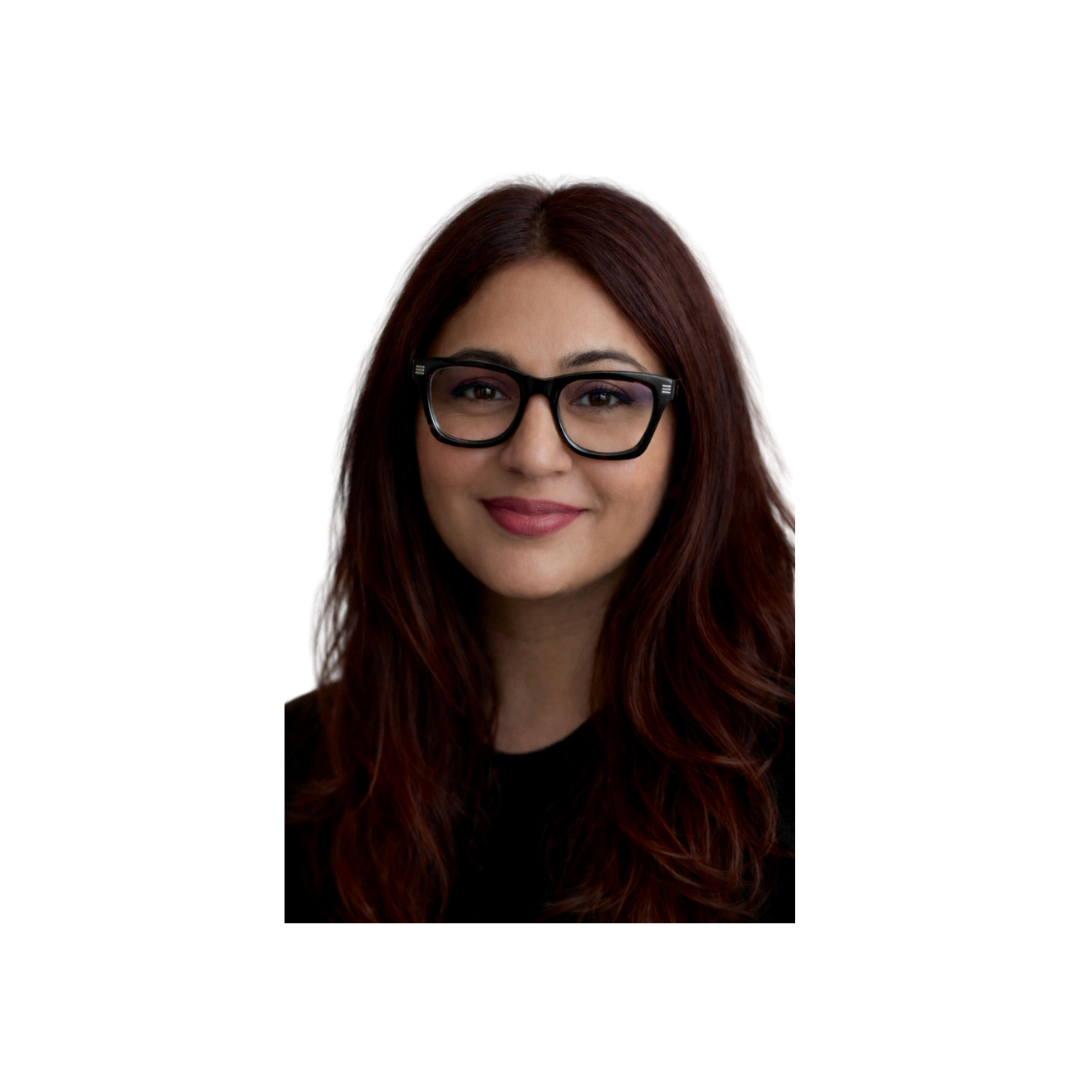A woman with long, wavy auburn hair wearing black glasses and a black top, smiling against a plain white background.