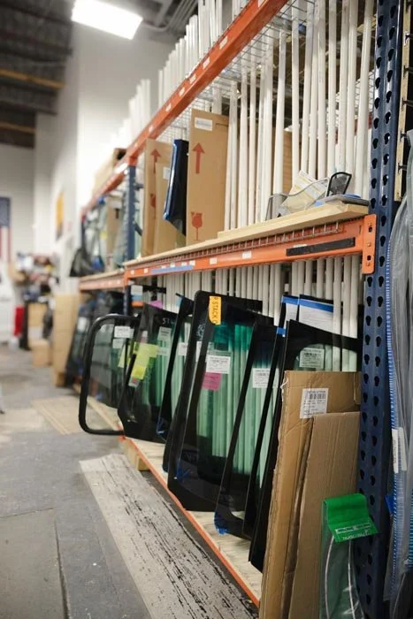 Store aisle with glass panes, tools, and hardware supplies on shelves.