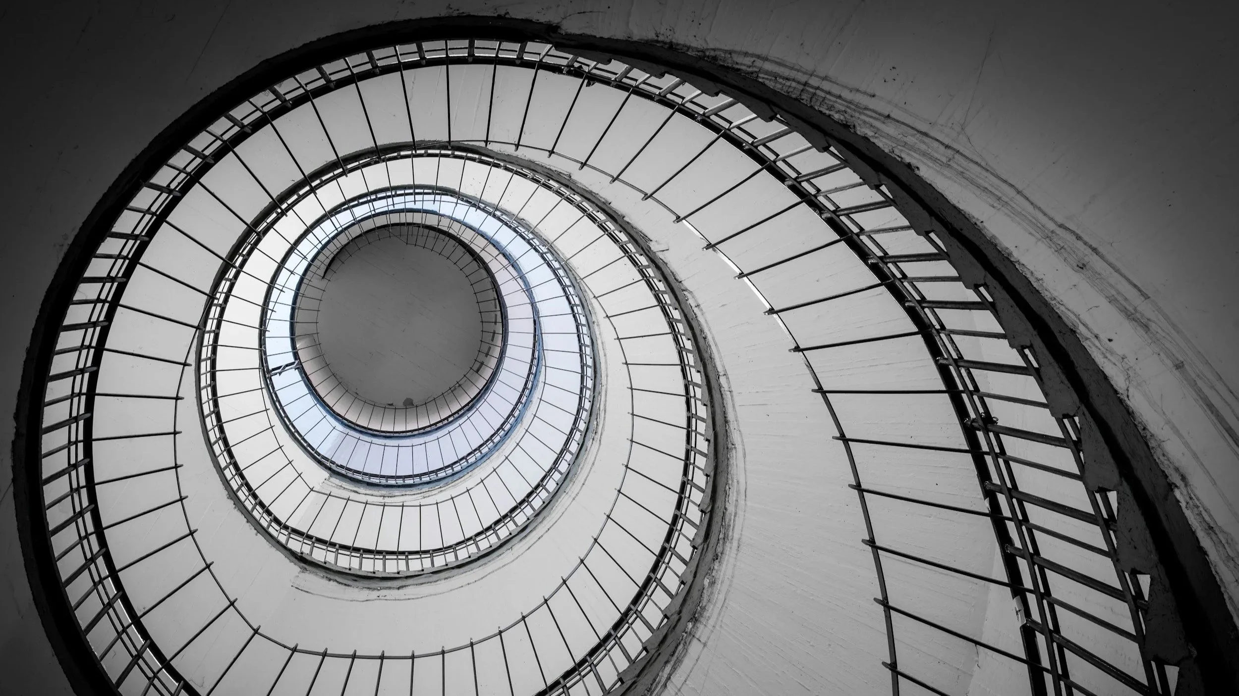 Looking up a spiral staircase from the bottom, showing a circular pattern with railings and steps.