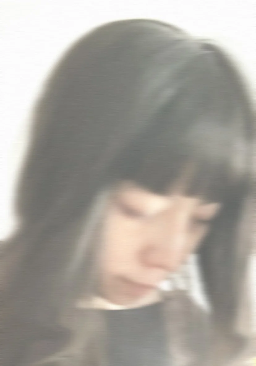 Blurry photo of a woman with long dark hair looking down.
