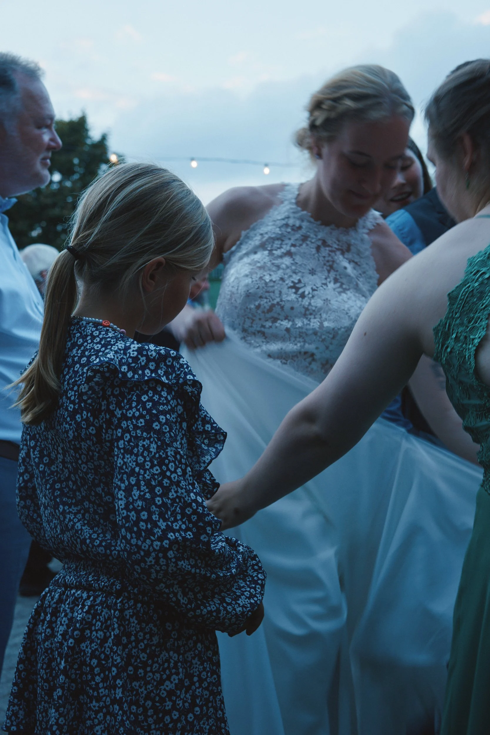 Mehrere Menschen, darunter eine Frau in einem weißen Kleid, die sich anscheinend bei einer Hochzeit befinden, halten sich an den Händen und binden sich wahrscheinlich beim Hochzeitsritual."}}#}  ASTE.jsnsyntaxerror: Input is not valid JSON. -- {
