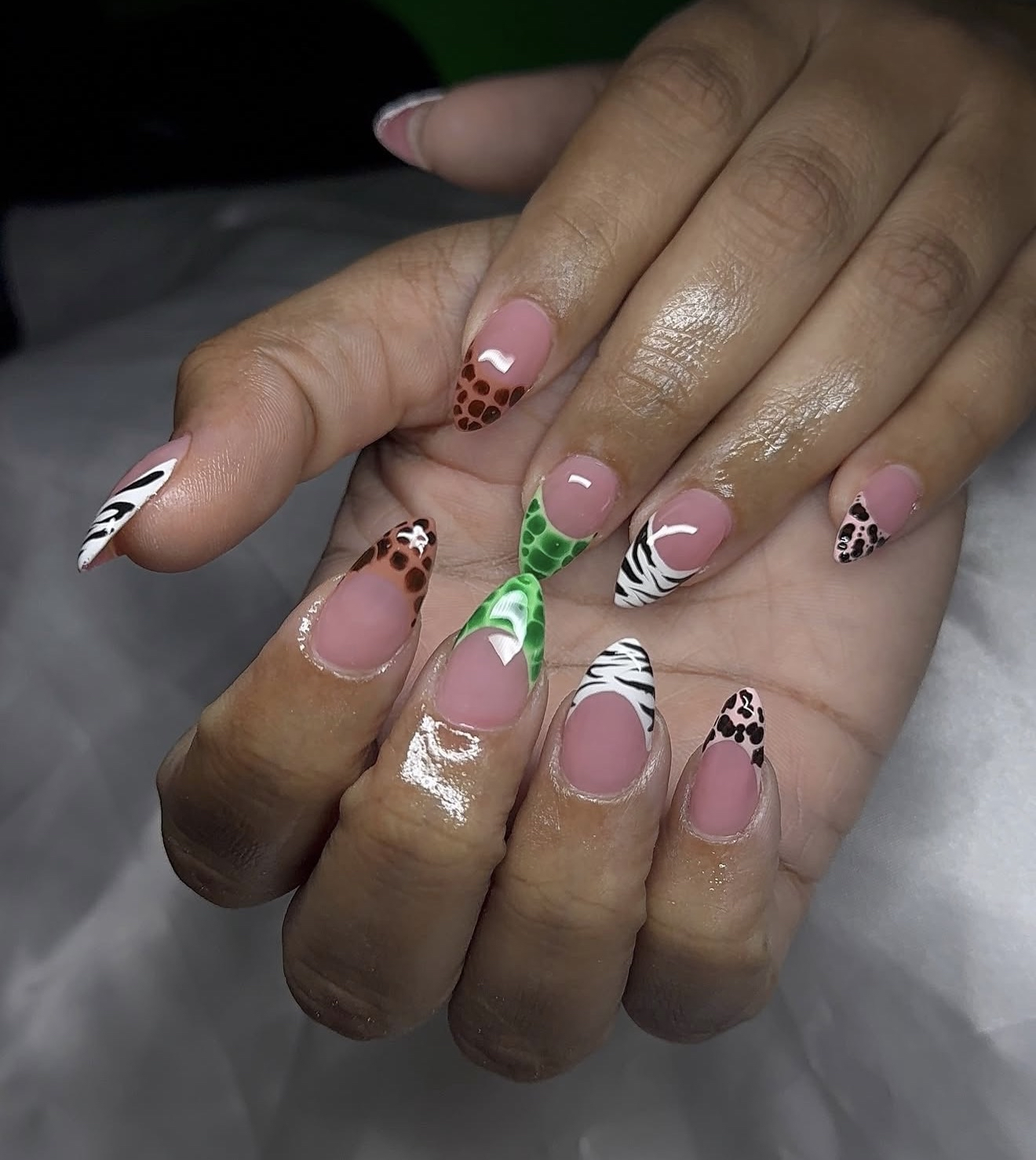 Close-up of a person's hands with manicured nails featuring animal print and colorful designs.