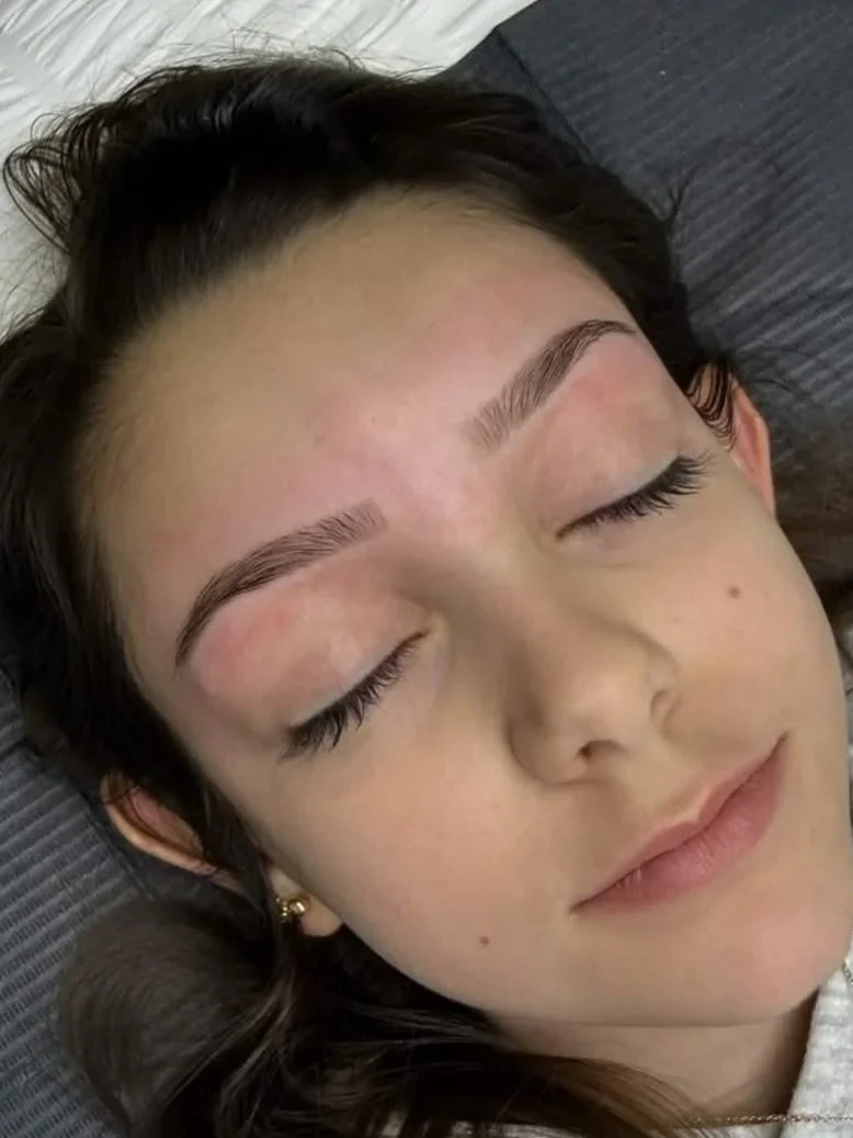 Close-up of a young woman sleeping with eyes closed, lying on a gray pillow.