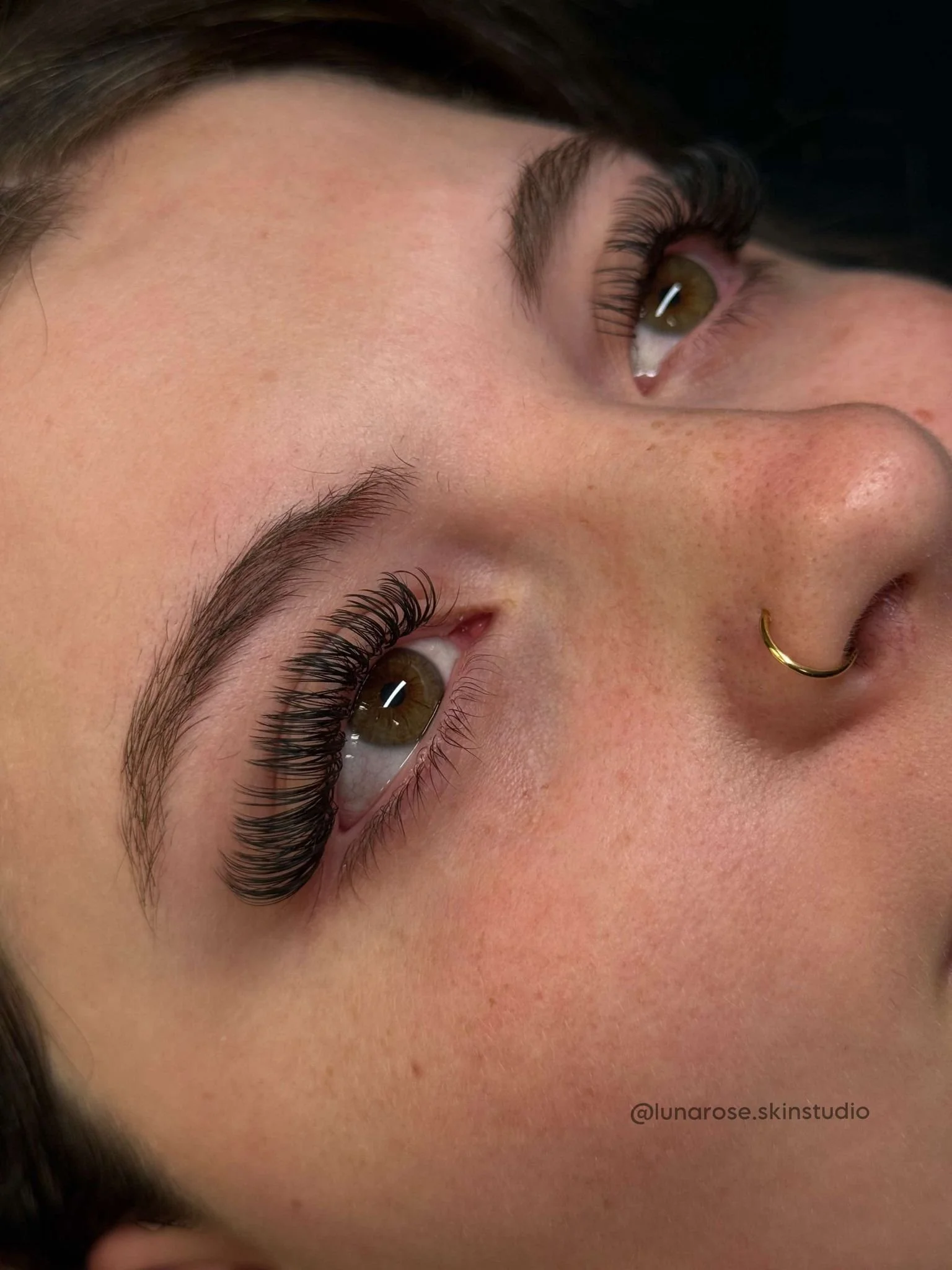 Close-up of a person's face focusing on the eye, eyebrow, nose, and part of their forehead, with the subject lying down and their eye looking slightly upward.
