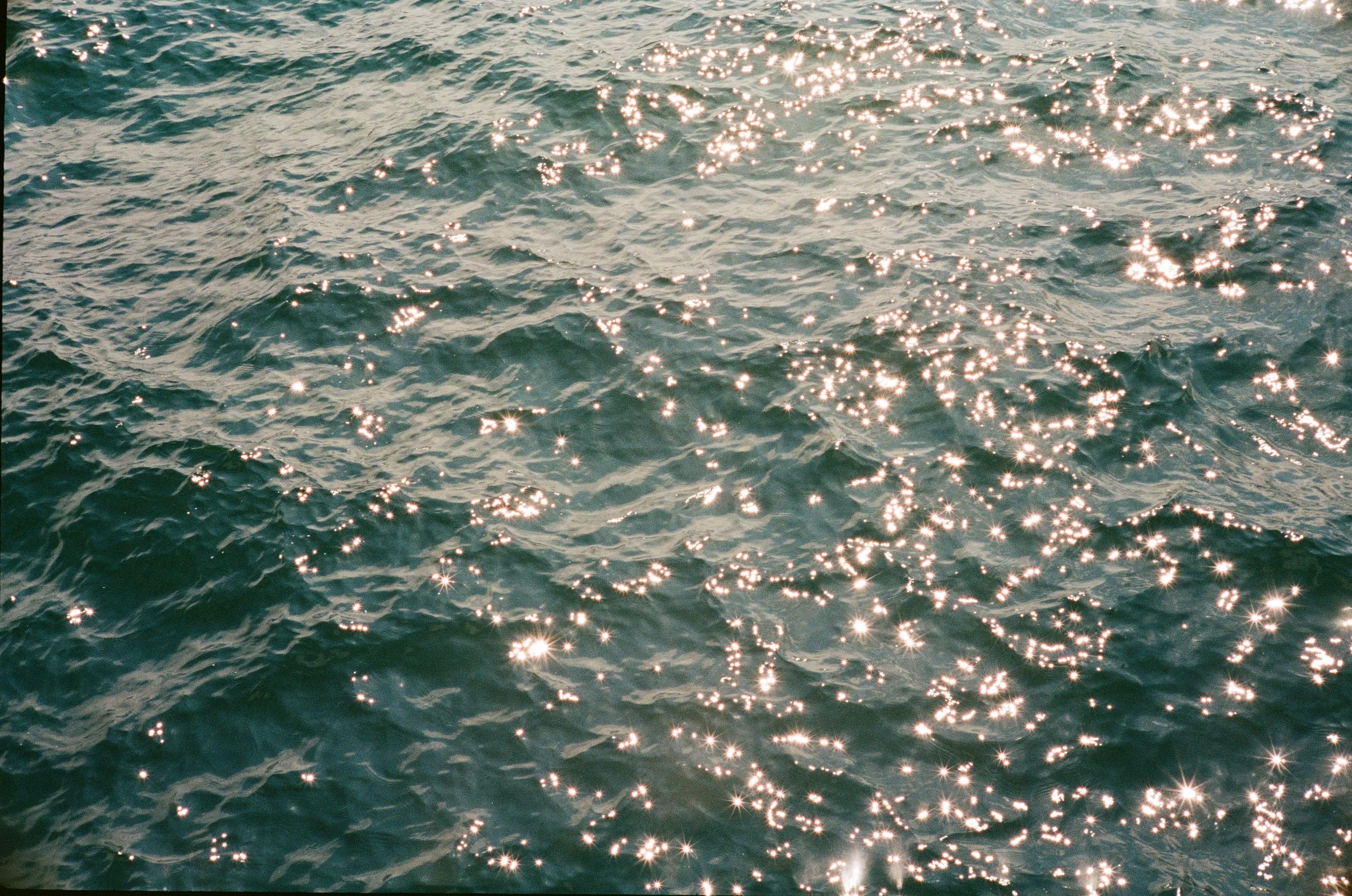 Sunlight reflecting off the surface of the ocean, creating sparkling highlights on the water.