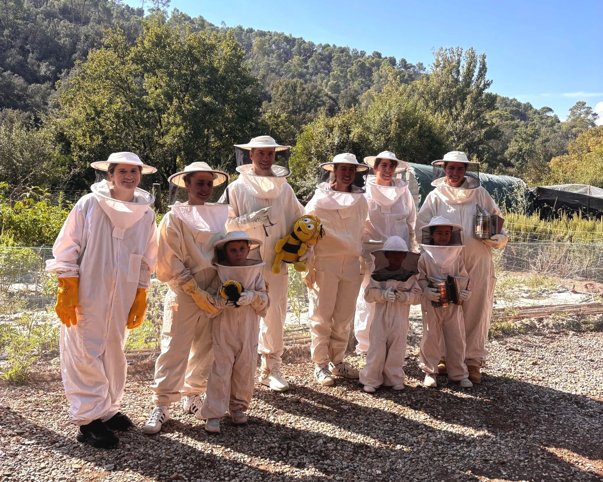 Participants in beekeeping suits looking into a hive
