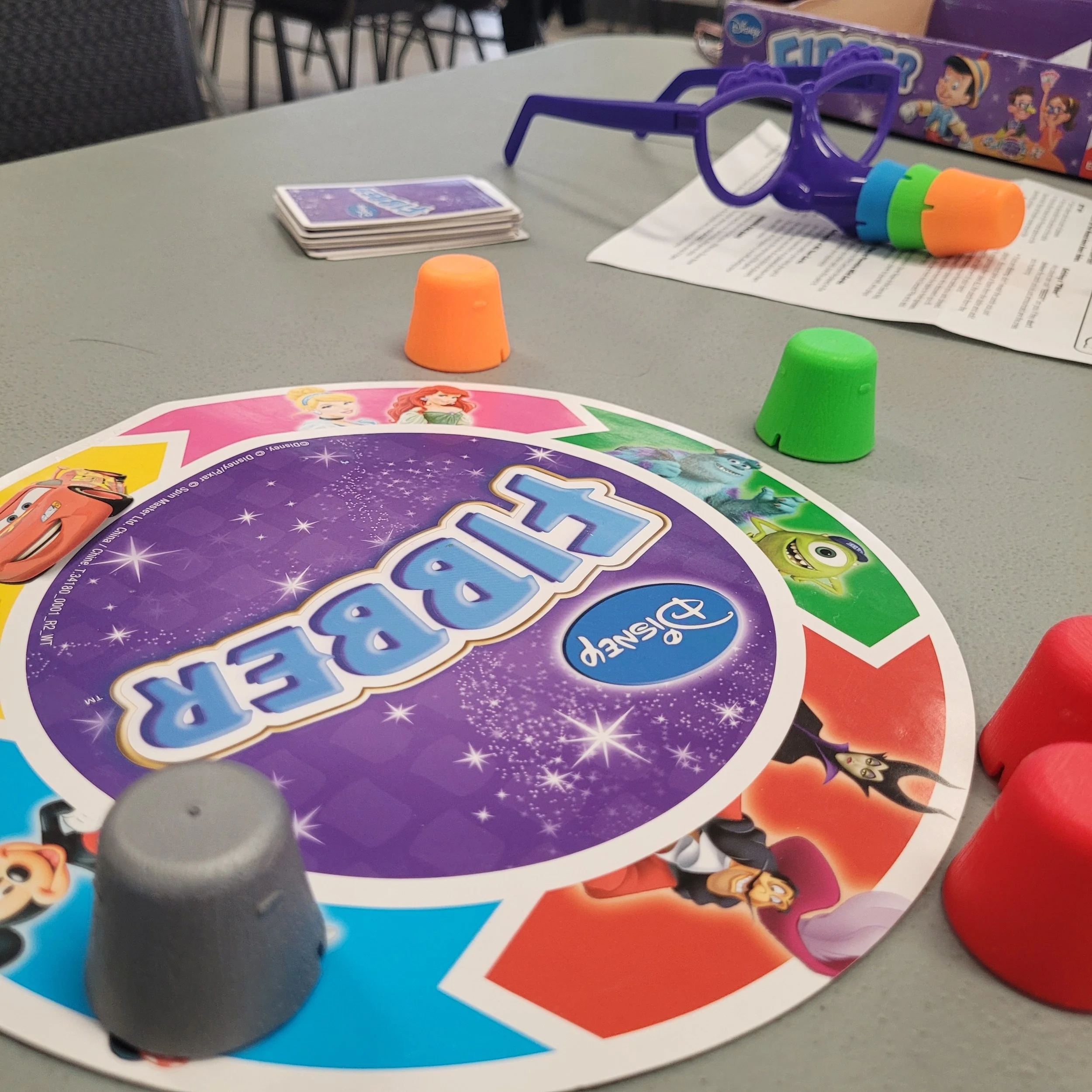 Close-up view of a board game setup on a table with colorful game pieces, cards, and instructions, featuring cartoon characters on the game board and box.
