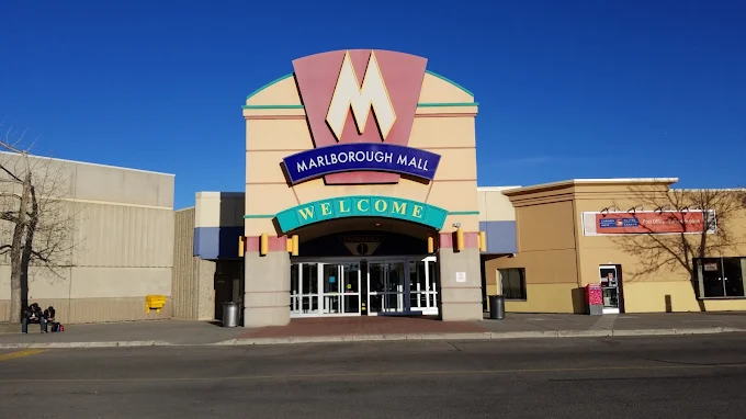 The entrance of Marlborough Mall with a large welcome sign and a prominent 'M' logo above the entrance, under a clear blue sky.