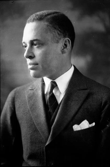 Black and white portrait of a man in a suit and tie, looking to the left.