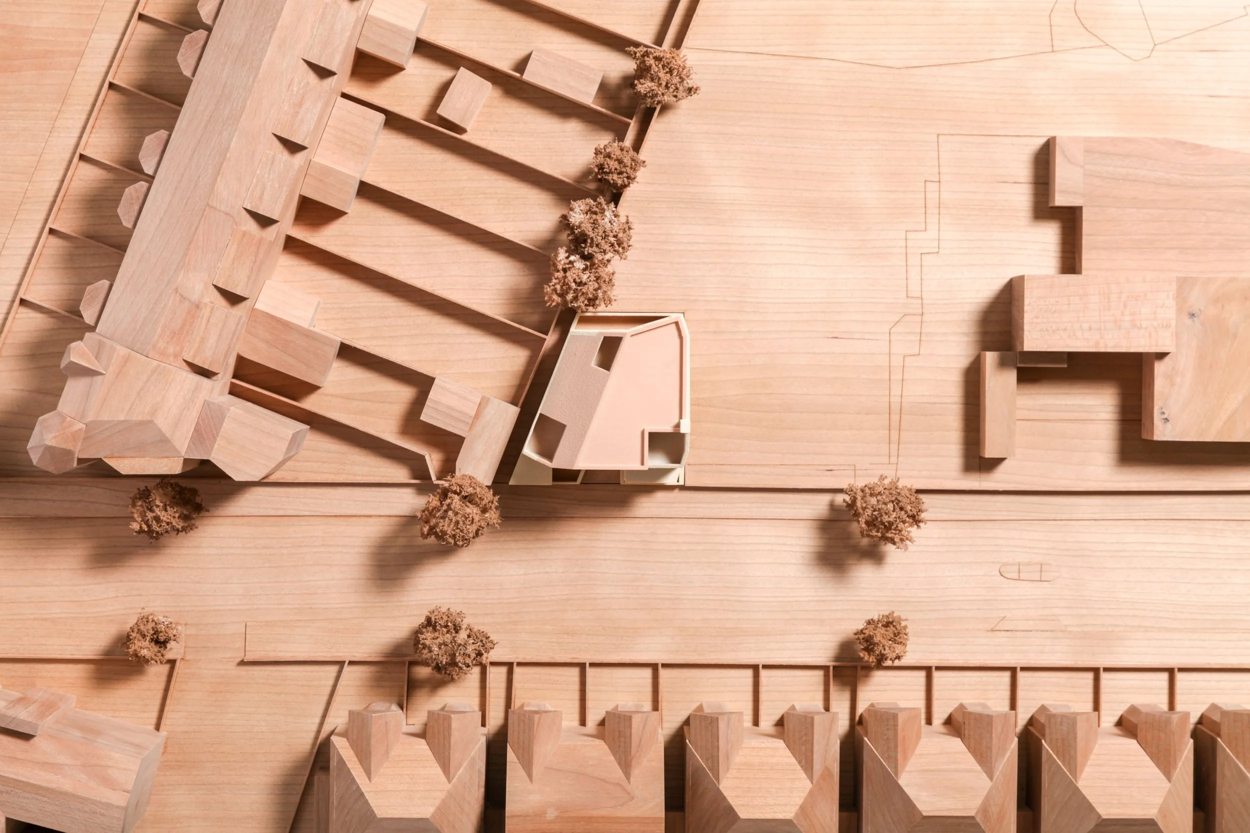 An architectural model of a construction site showing wooden buildings, trees, and roads.