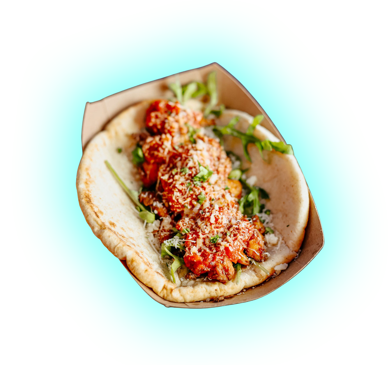 Close-up of three meatballs in a bun with tomato sauce, topped with grated cheese and chopped green herbs, served in a paper tray with some green vegetables on the side.