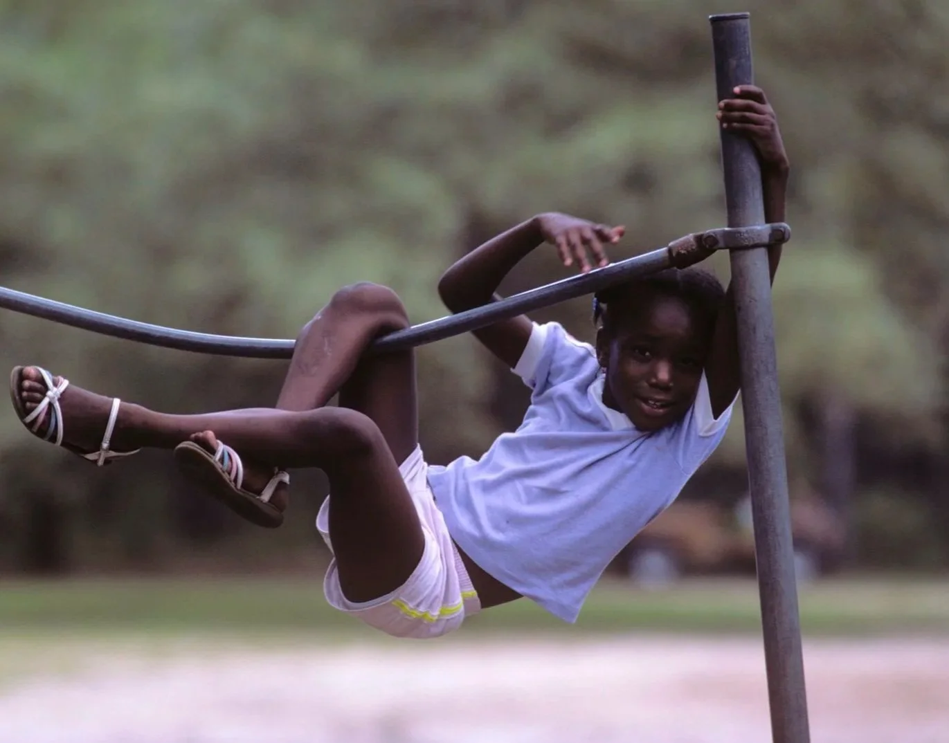 Historical image from 1987 of a Gullah Geechee girl climbing and playing on metal poles.
