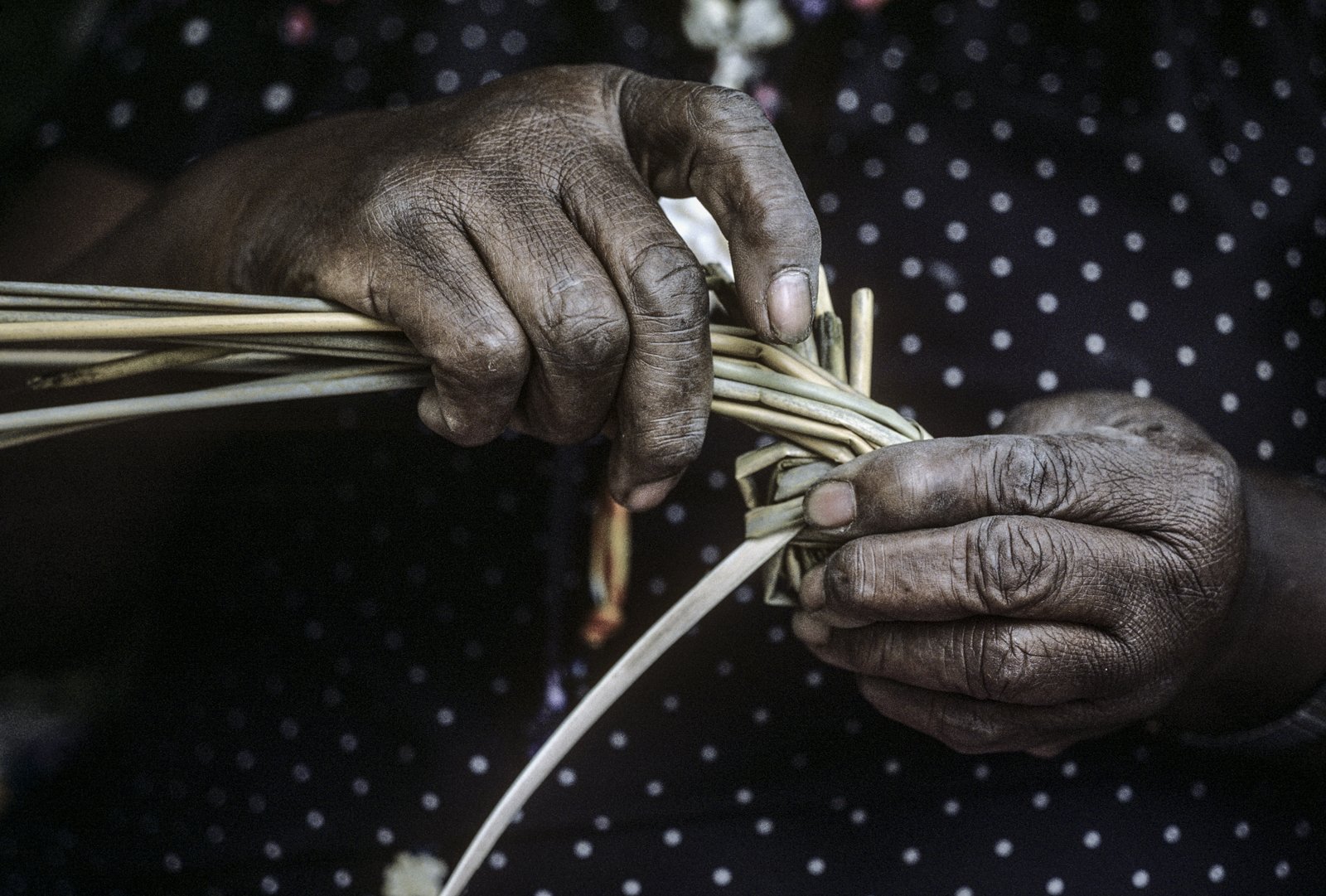 Historical image from 1987 of a woman's hands making a sweetgrass basket.