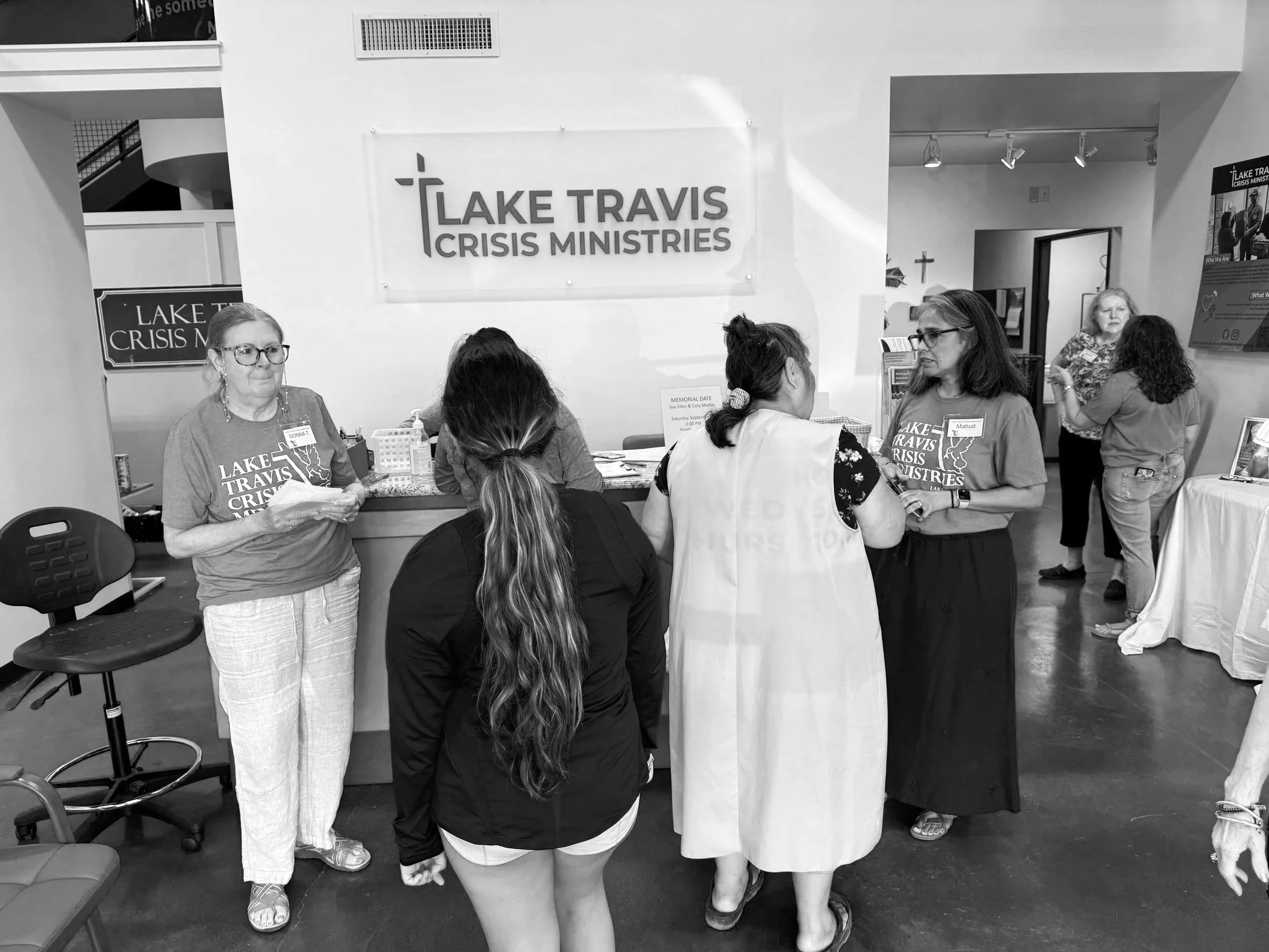 Group of people in an indoor space at a nonprofit organization called Lake Travis Crisis Ministries, engaging in conversation.