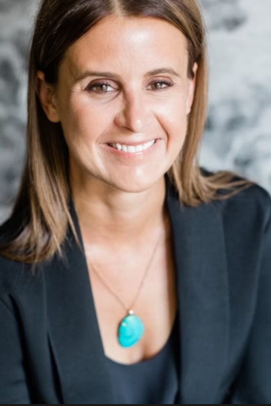 Headshot of Rachel White in a blazer with turquoise necklace