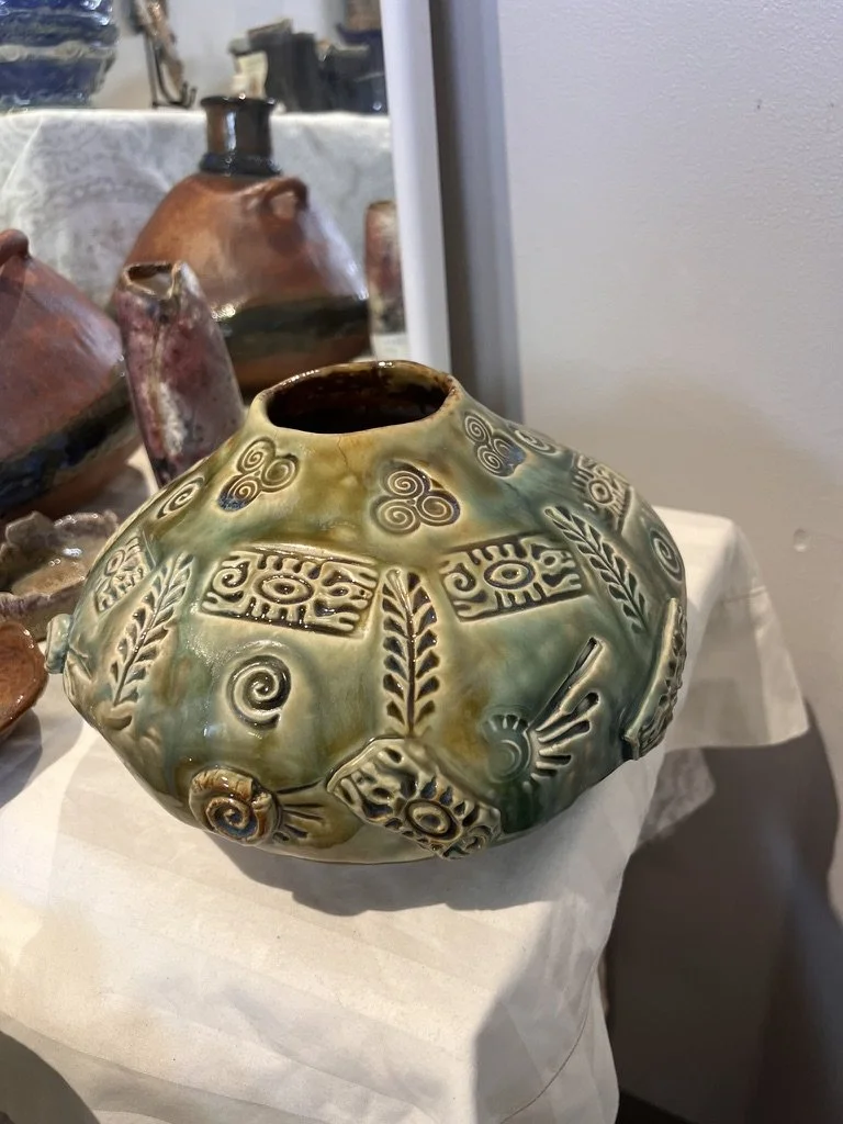 Stoneware water-carrier vessel with green glaze, patterned surface, and organic rounded form.
