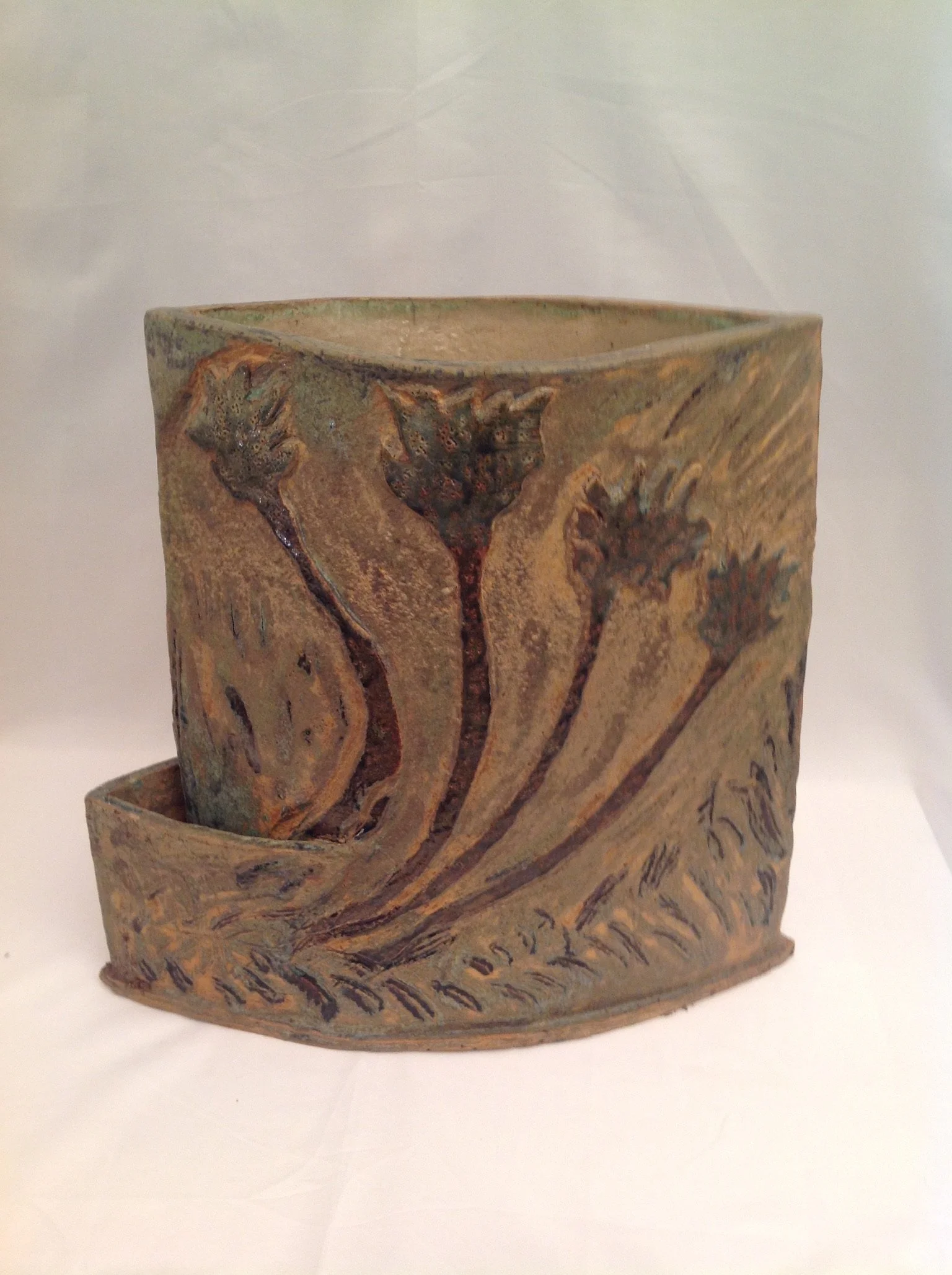 Stoneware planter with stamped plant forms, earthy texture, and warm desert-toned clay.