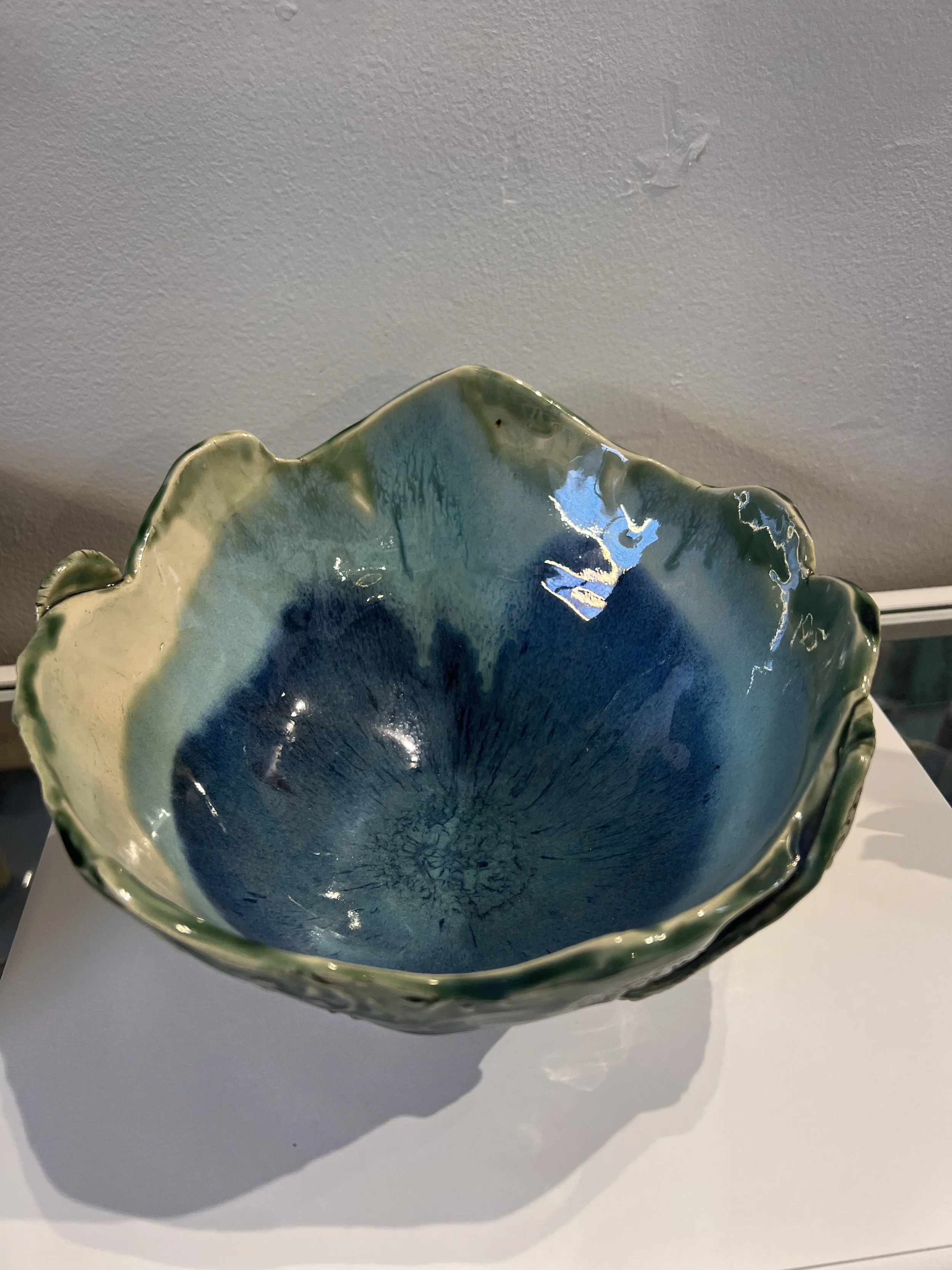 Blue-green glazed stoneware bowl with scalloped rim and glossy interior, photographed from above.