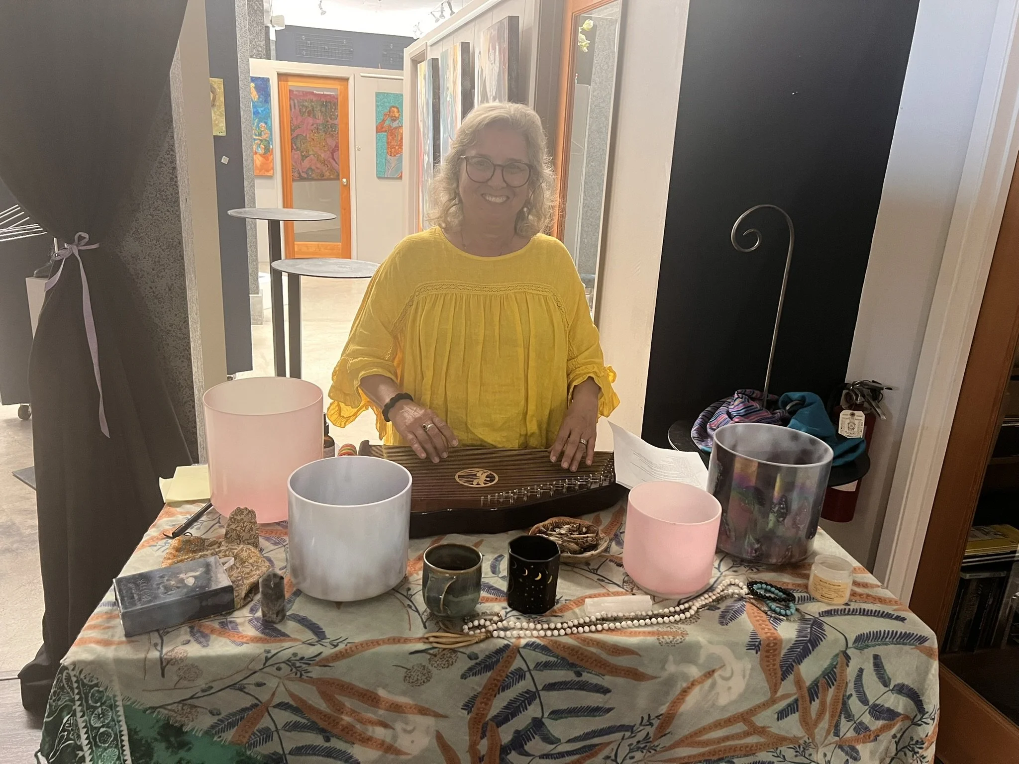 Karen playing her therapy harp surrounded by healing sound bowls.