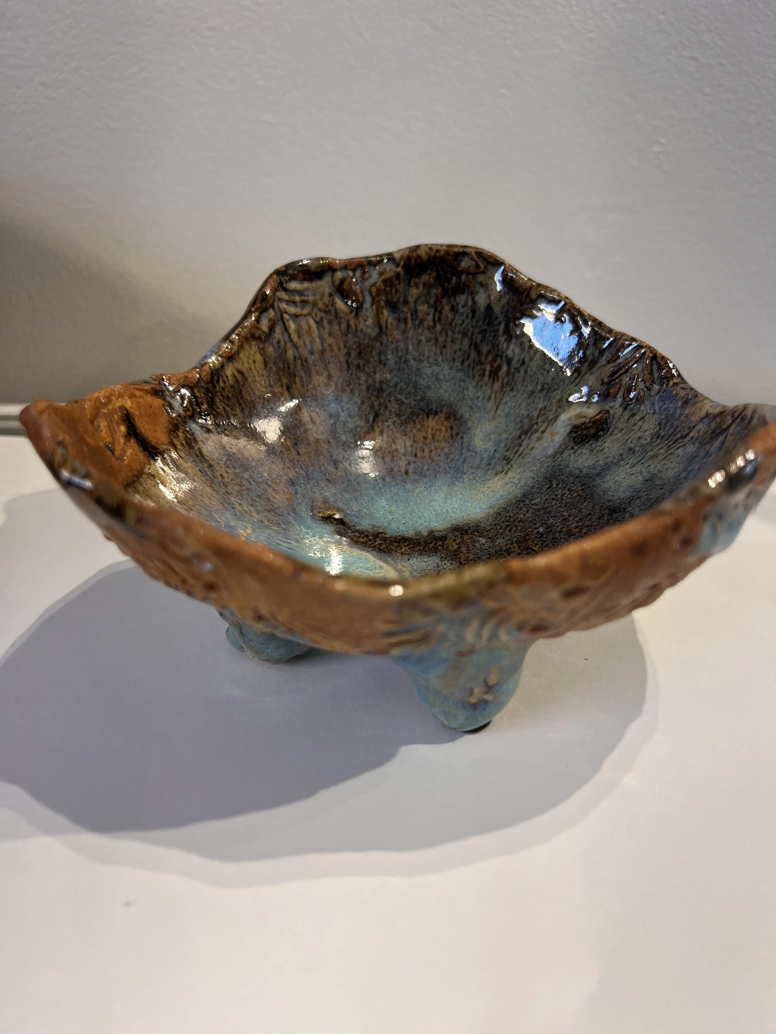 Side view of stoneware bowl with dark blue interior, earthy orange edge, and raised base.