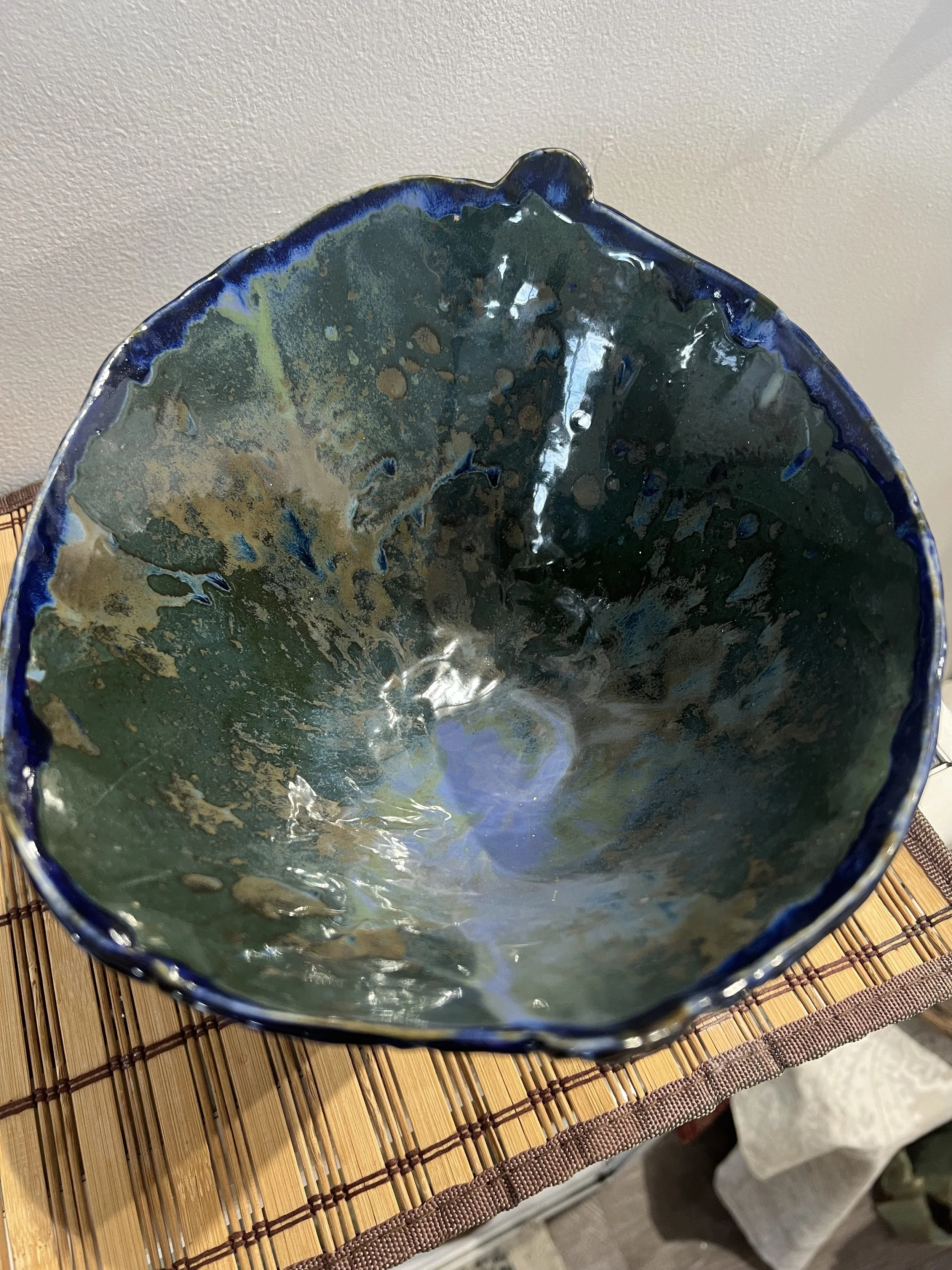 Overhead view of glossy blue-green stoneware bowl with rounded interior and organic glazed texture.