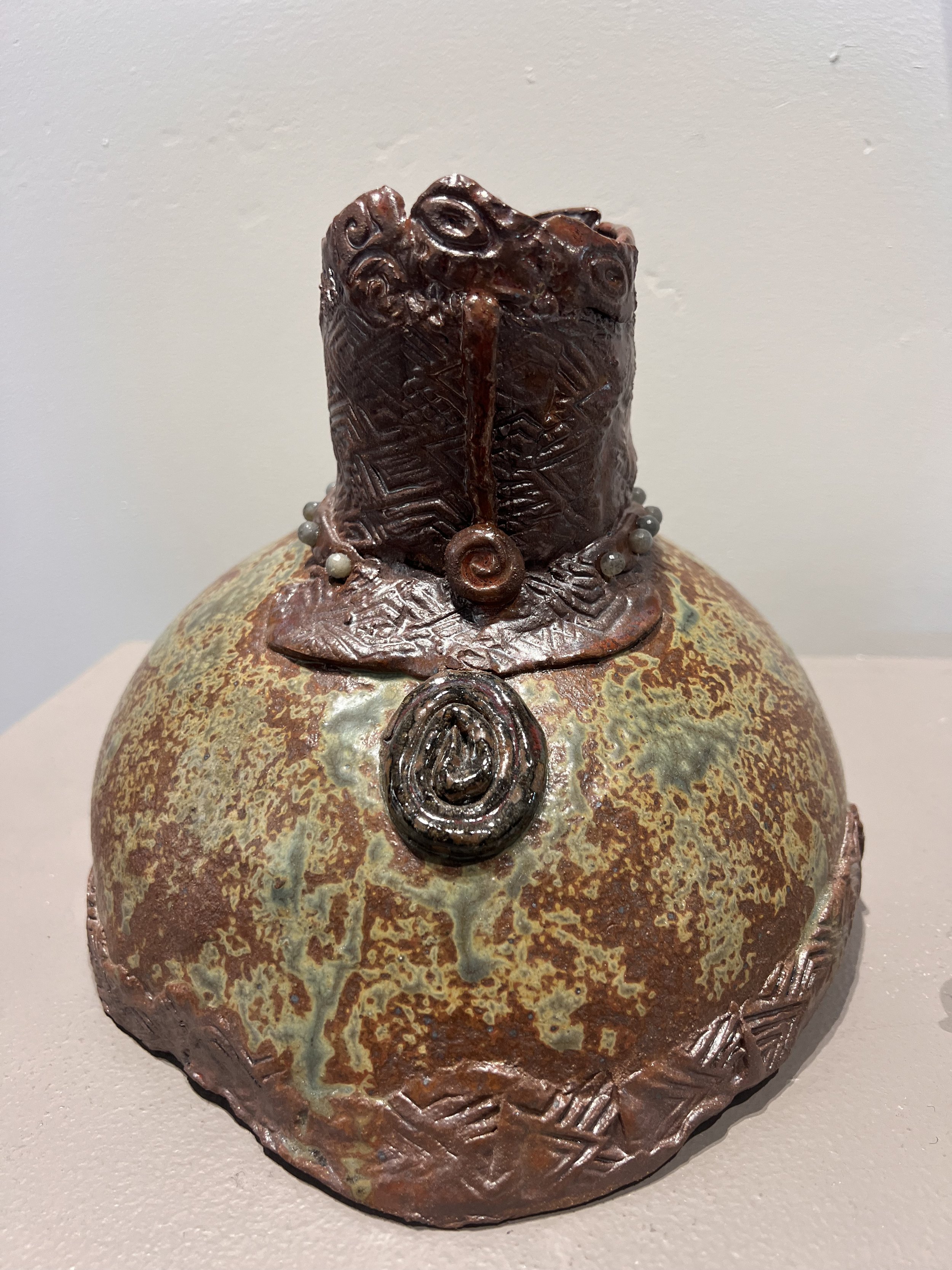 Front view of Warrior Goddess stoneware vase with earthy glaze and circular pendant-like detail.