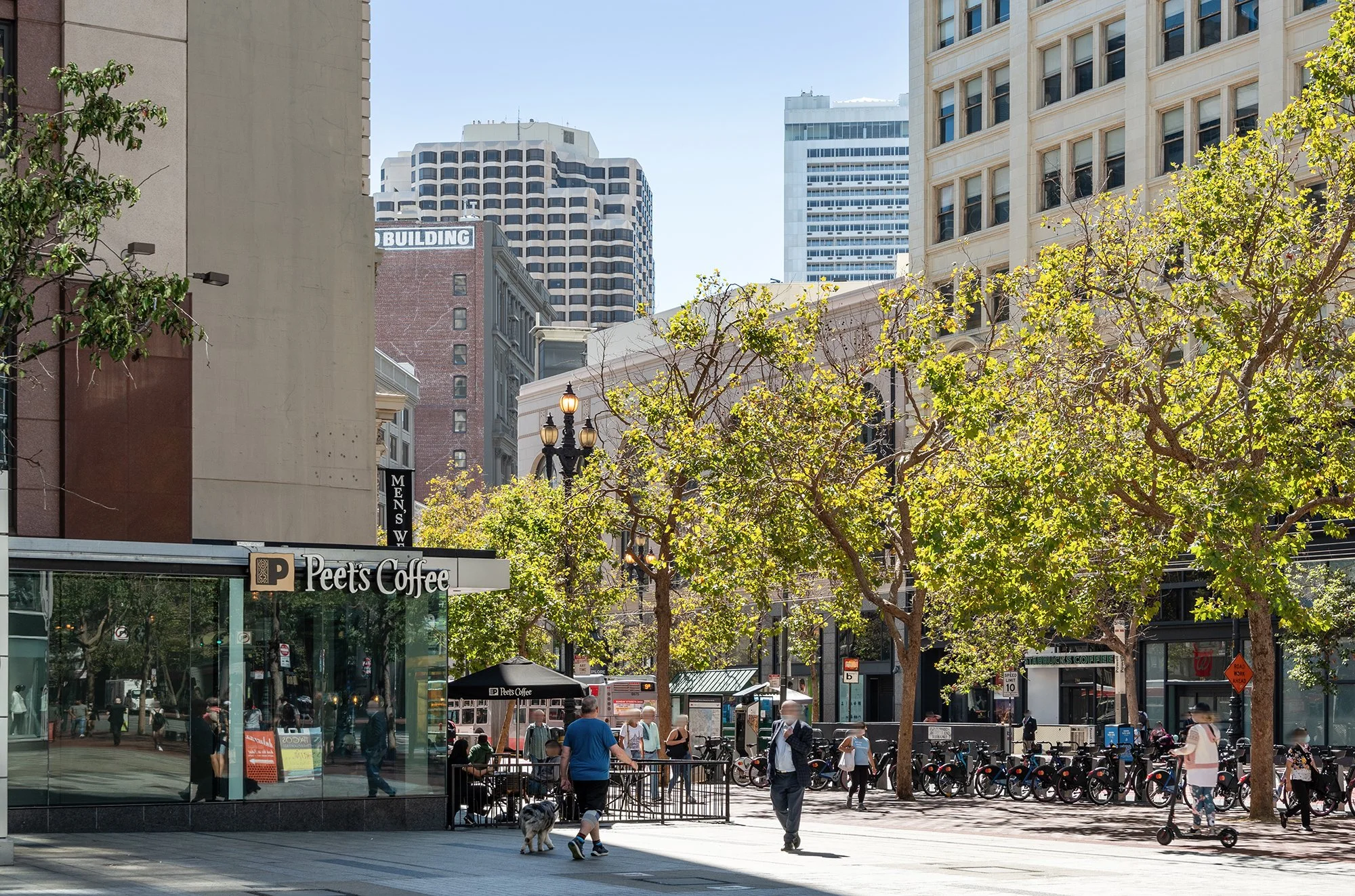 Urban street scene with trees, pedestrians, and a Peet's Coffee shop on the corner in downtown.