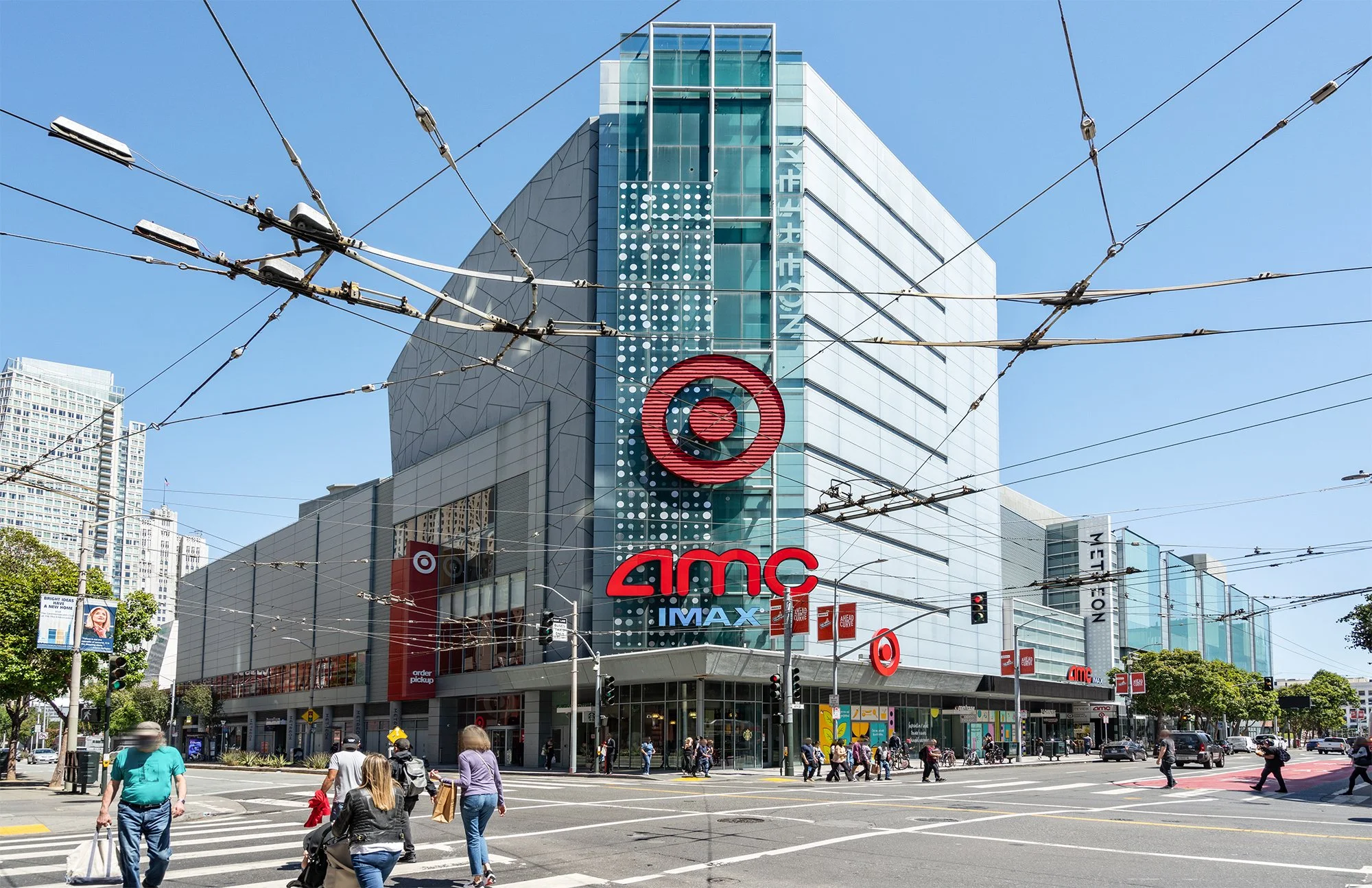 Target store on a busy city street with pedestrians crossing and traffic lights, showing the Target logo and signage for AMC IMAX theater.