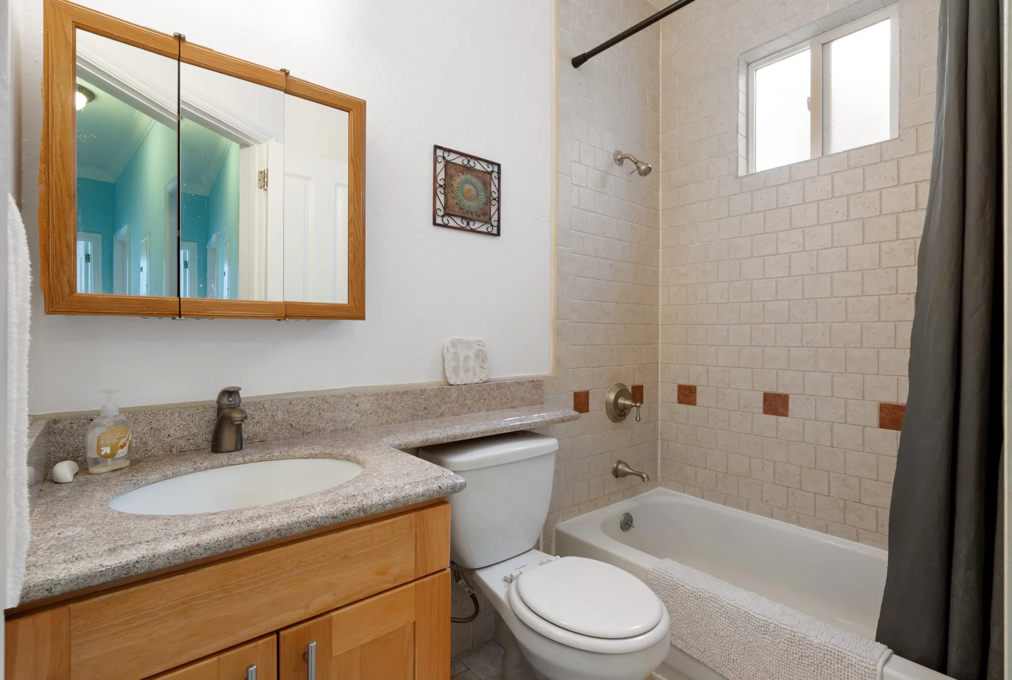 Bathroom with vanity, mirror, toilet, bathtub, and small frosted window.
