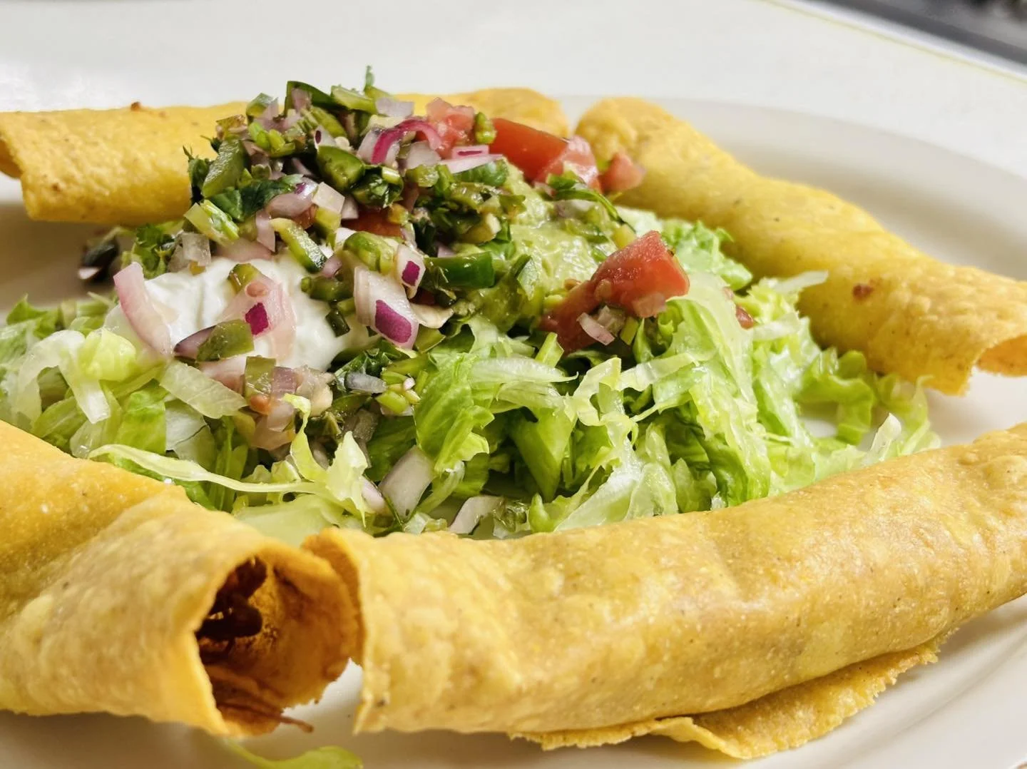 A Caesar salad served in a crispy taco shell bowl, garnished with chopped lettuce, tomatoes, chopped onions, and croutons.