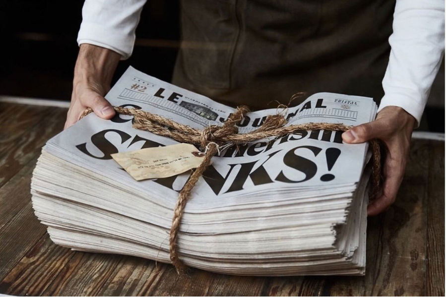 Man grabs a stack of twine tied newspapers