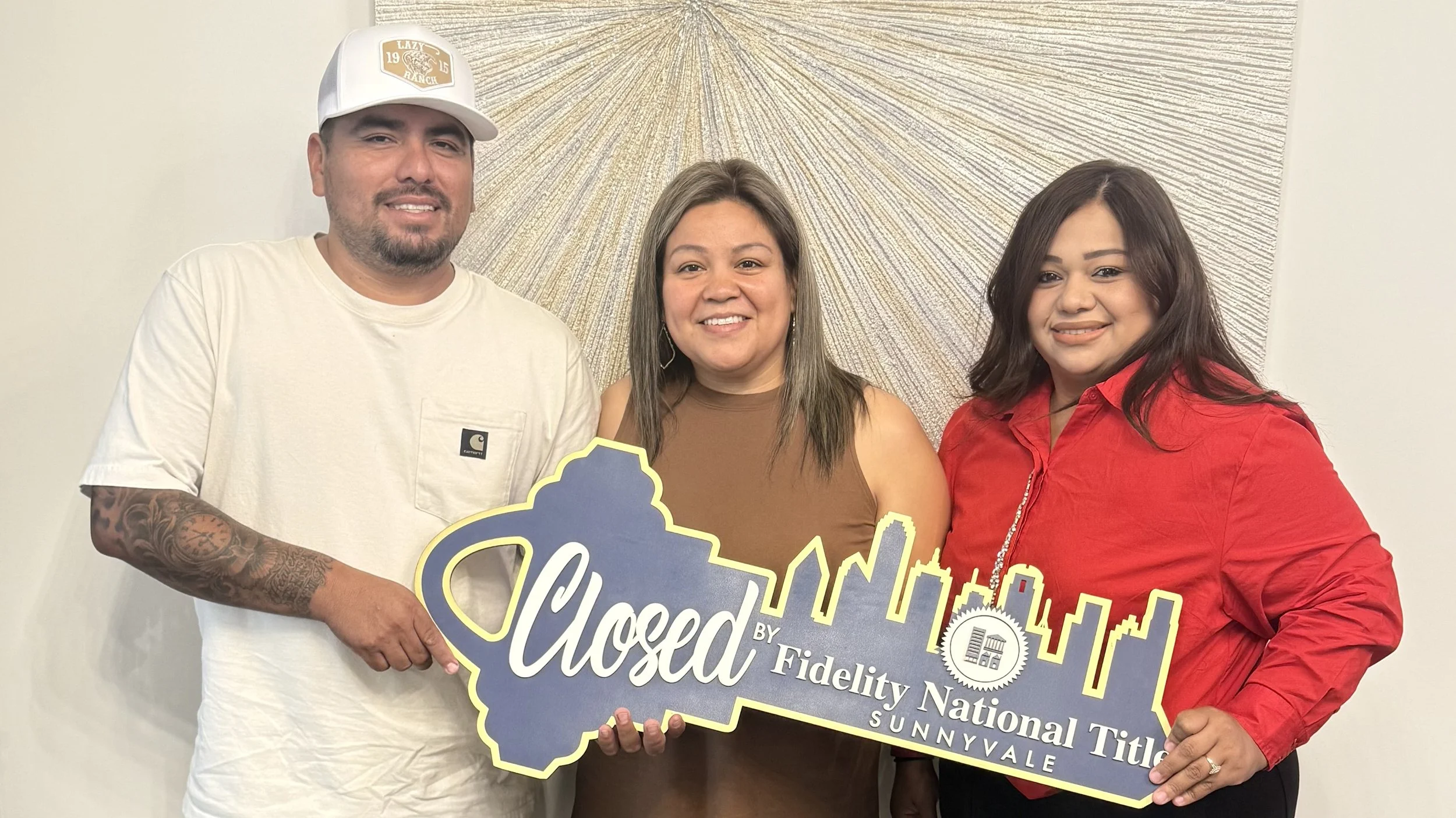 Three people standing together, holding a sign that reads "Closed by Fidelity National Title Sunnyvale" with a city skyline in the background. Sold happy clients.