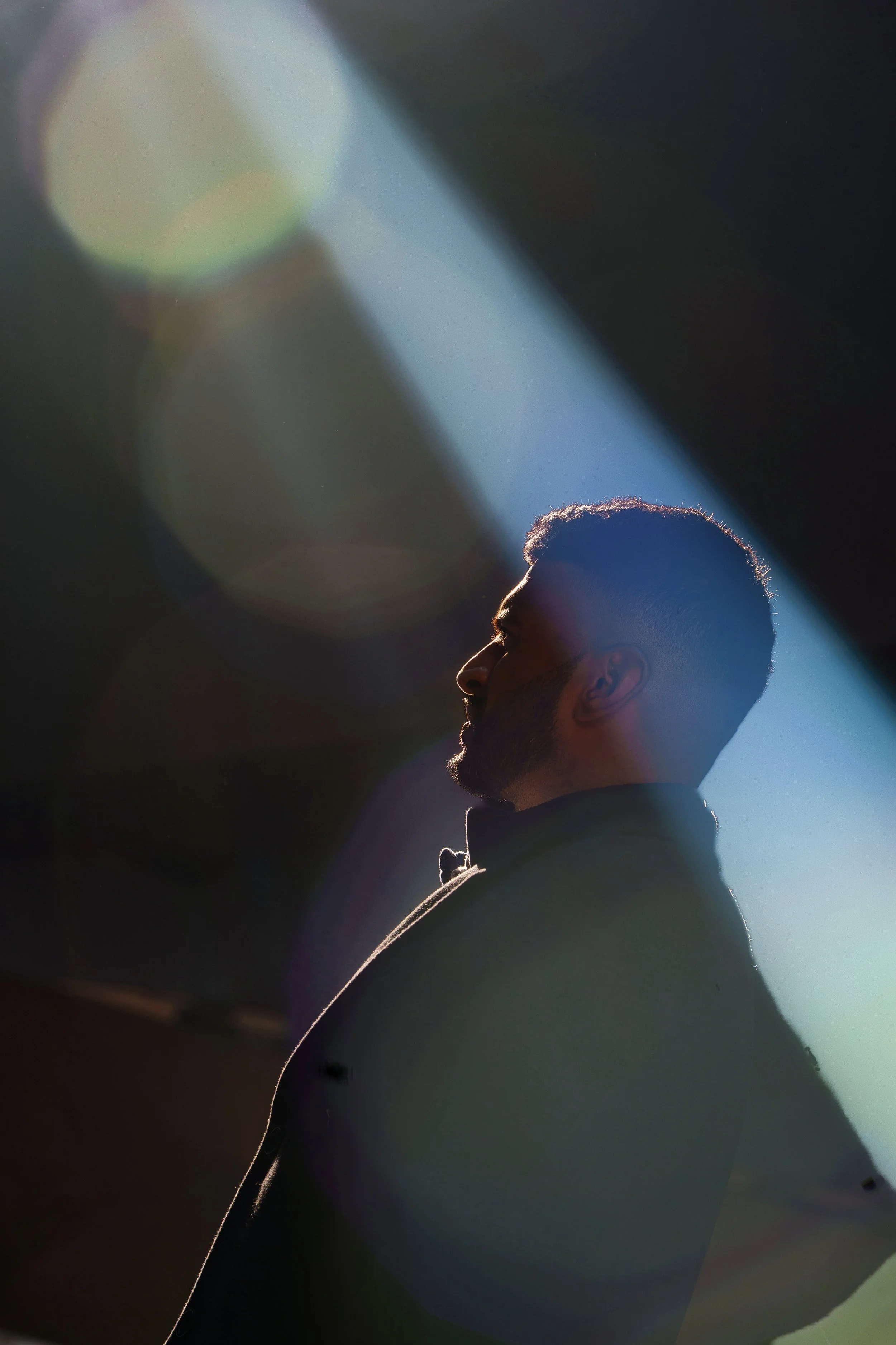 Private recovery coaching, family support, intervention guidance, and safe passage for individuals and families readSilhouette of a man with short hair and a beard, looking upwards, with sunlight creating a halo effect and lens flare around his head.