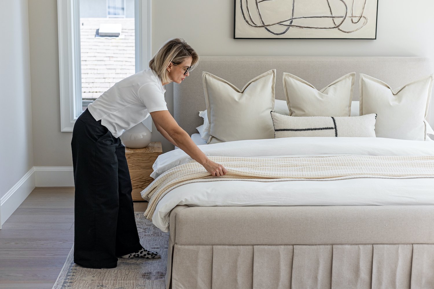 Professional home stager styling a bed during vacant home staging — The Design Alchemist Vancouver Lower Mainland