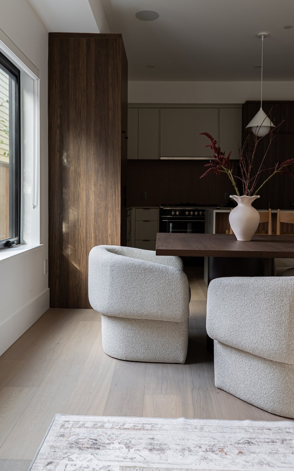 Staged open plan dining and kitchen with bouclé chairs and warm walnut tones — professional home staging Vancouver Lower Mainland by The Design Alchemist