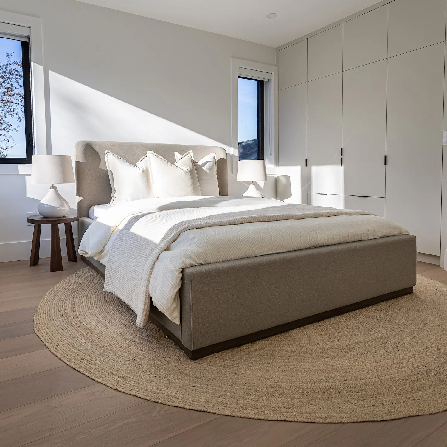 Layered bed styling in a Kitsilano home with a warm and inviting feel