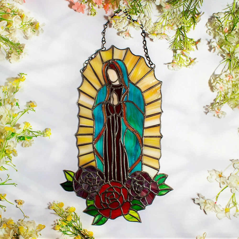 Stained glass depiction of Virgin Mary surrounded by flowers and foliage.
