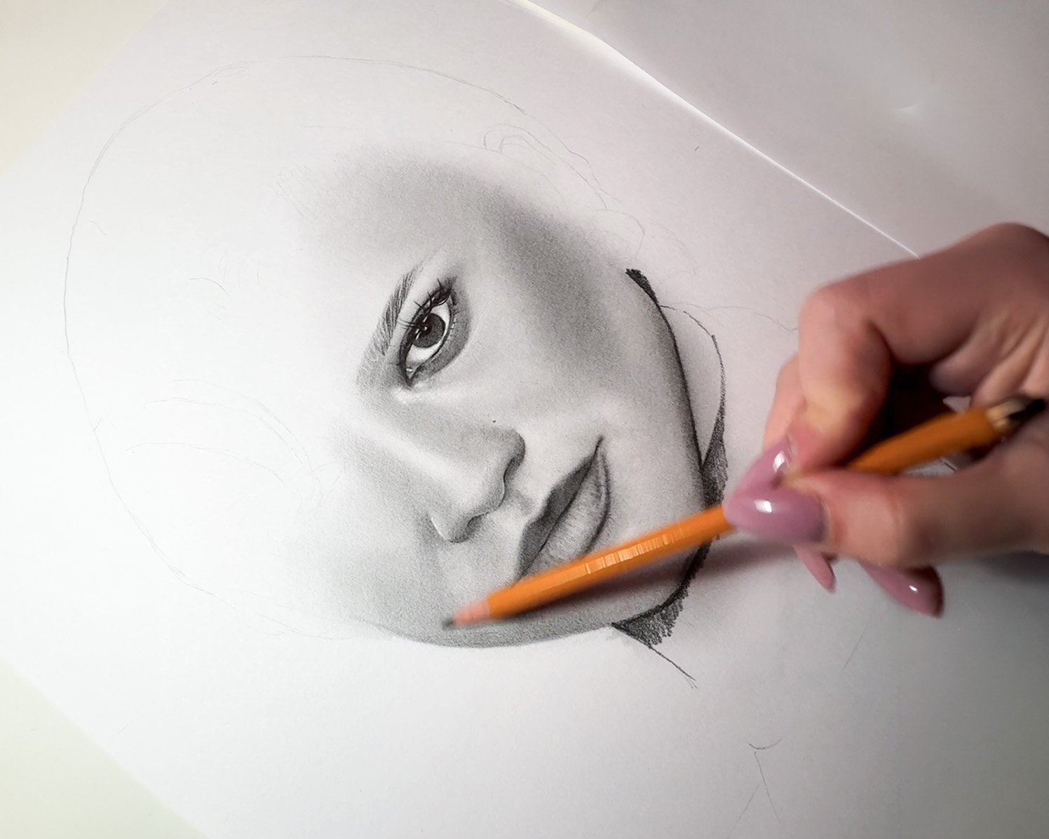 Person sketching with colored pencils on paper, surrounded by various drawing tools and sketches on a wooden table.