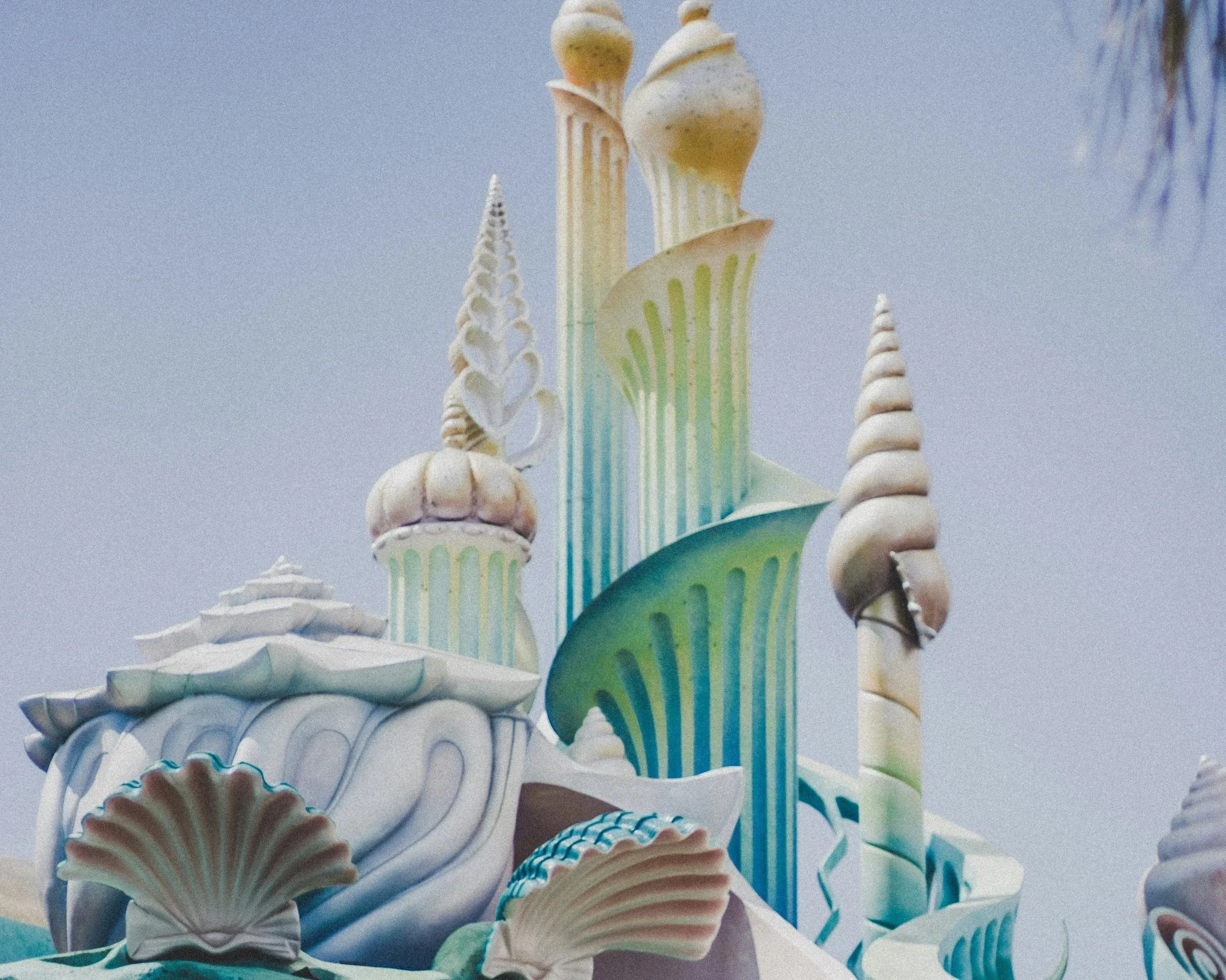 Colorful, whimsical castle structure with shell and conch shell motifs, featuring tall, twisted towers and pastel colors.