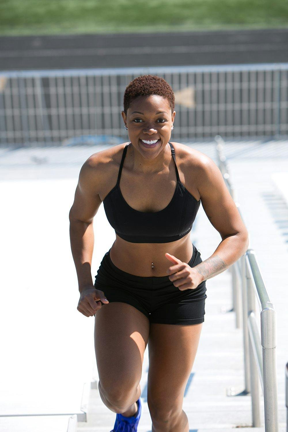 A woman in athletic attire running up outdoor stairs with a smile
