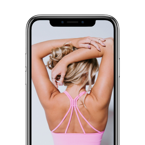 A woman in a pink sports bra stretching with her hands behind her head, seen through a smartphone front camera.