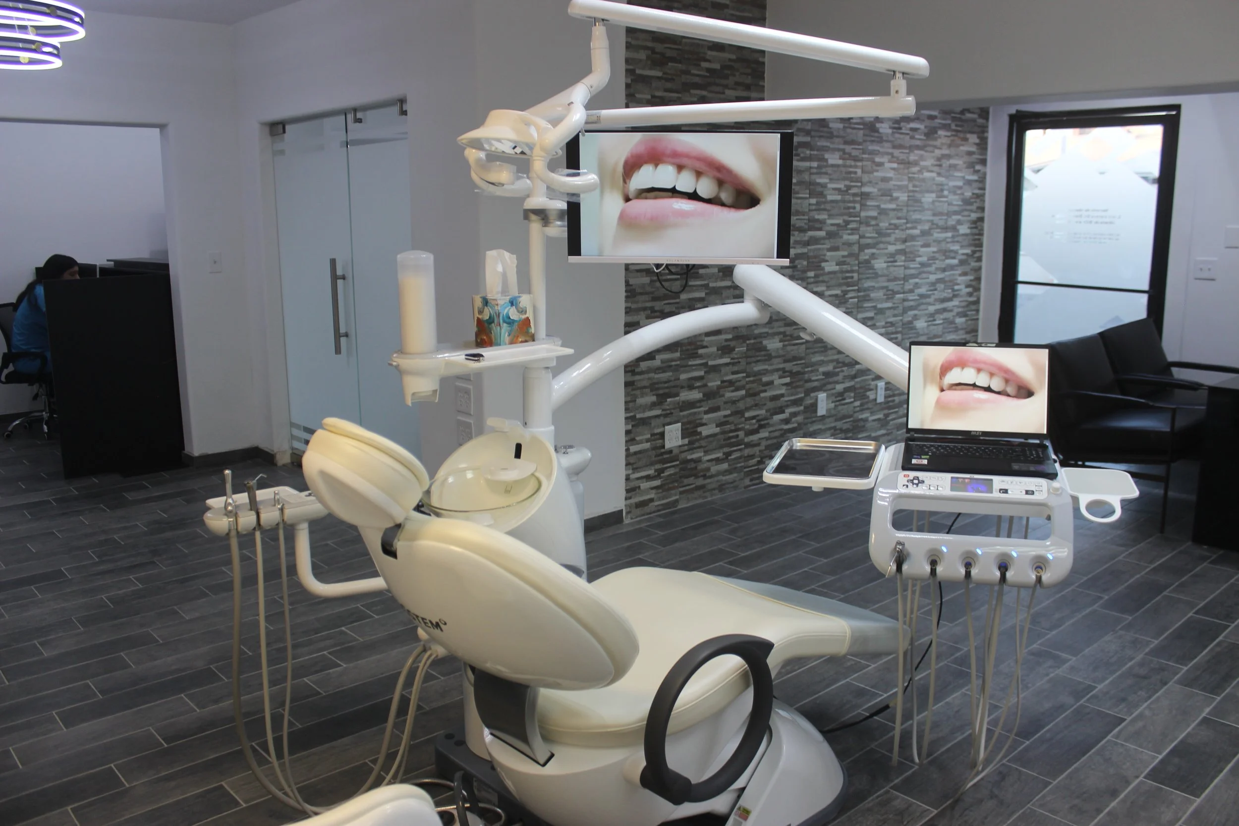 Silla de dentista en clínica dental con pantallas que muestran una sonrisa.