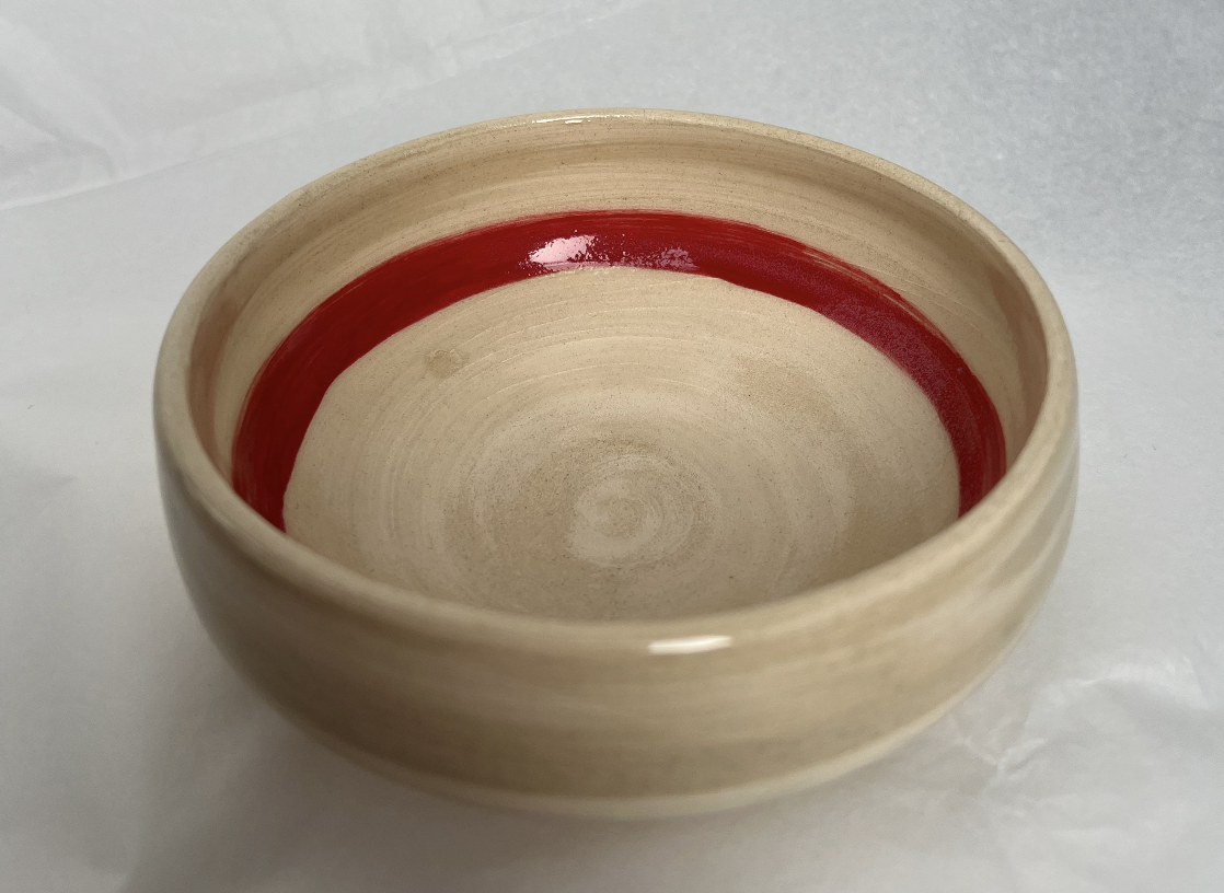 Cream-colored ceramic bowl with a red stripe near the top interior edge