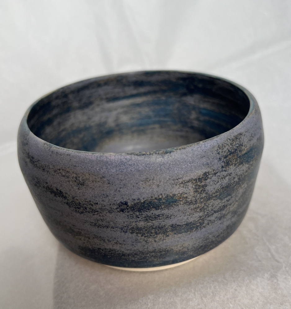 A round, blue and gray marbled ceramic bowl on a white surface.