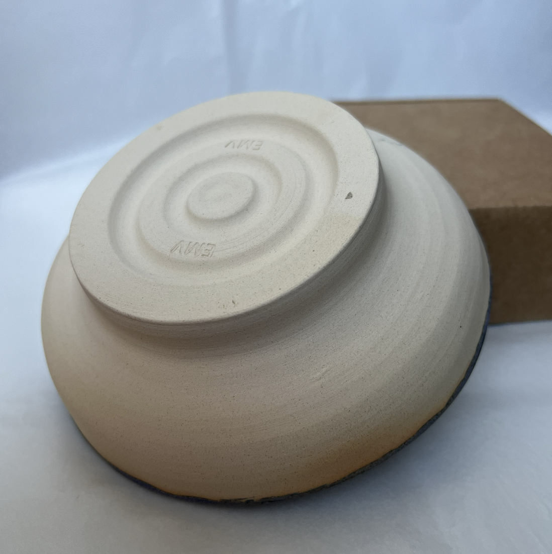 A beige ceramic bowl placed upside down on a surface