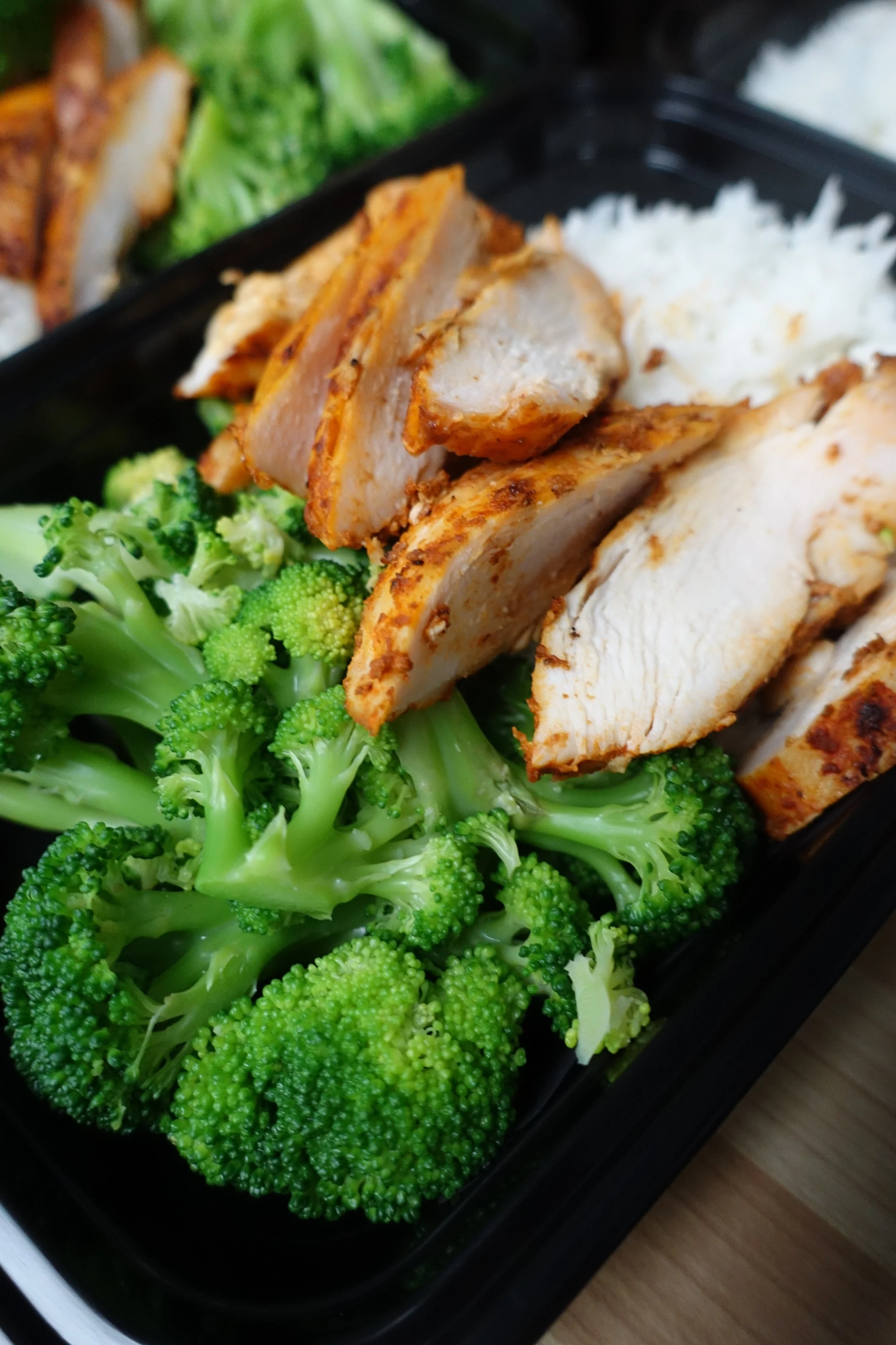 Grilled chicken breast with broccoli and white rice in a black container