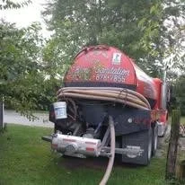 Fire responder truck with a hose attached in a grassy area with trees in the background.