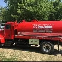 Red water tanker truck with text 'C.T. Fire Department' on the side, parked on a street with green trees in the background.