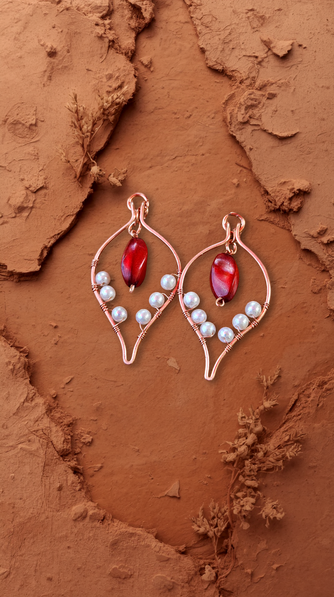 A pair of earrings with red and white beads on a textured, earthy-toned background.