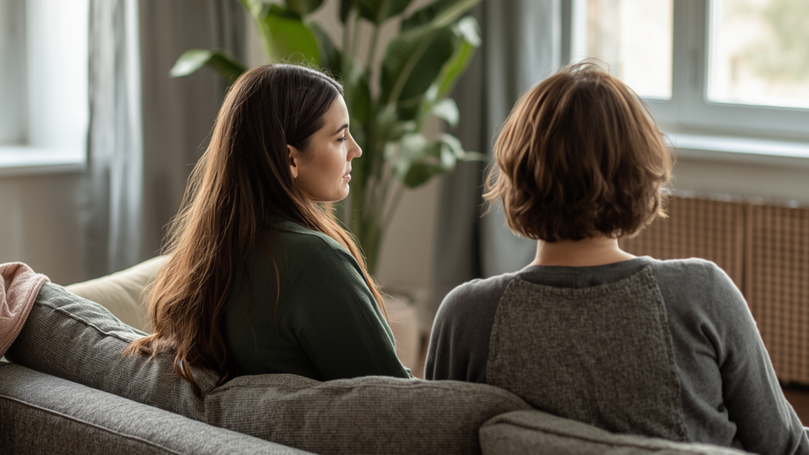 Two women and sitting on a couch, one woman providing comfort to the other during grief and loss